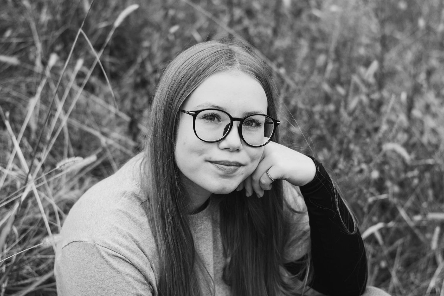 Black and white portrait series showing relaxed outdoor poses against natural backgrounds.