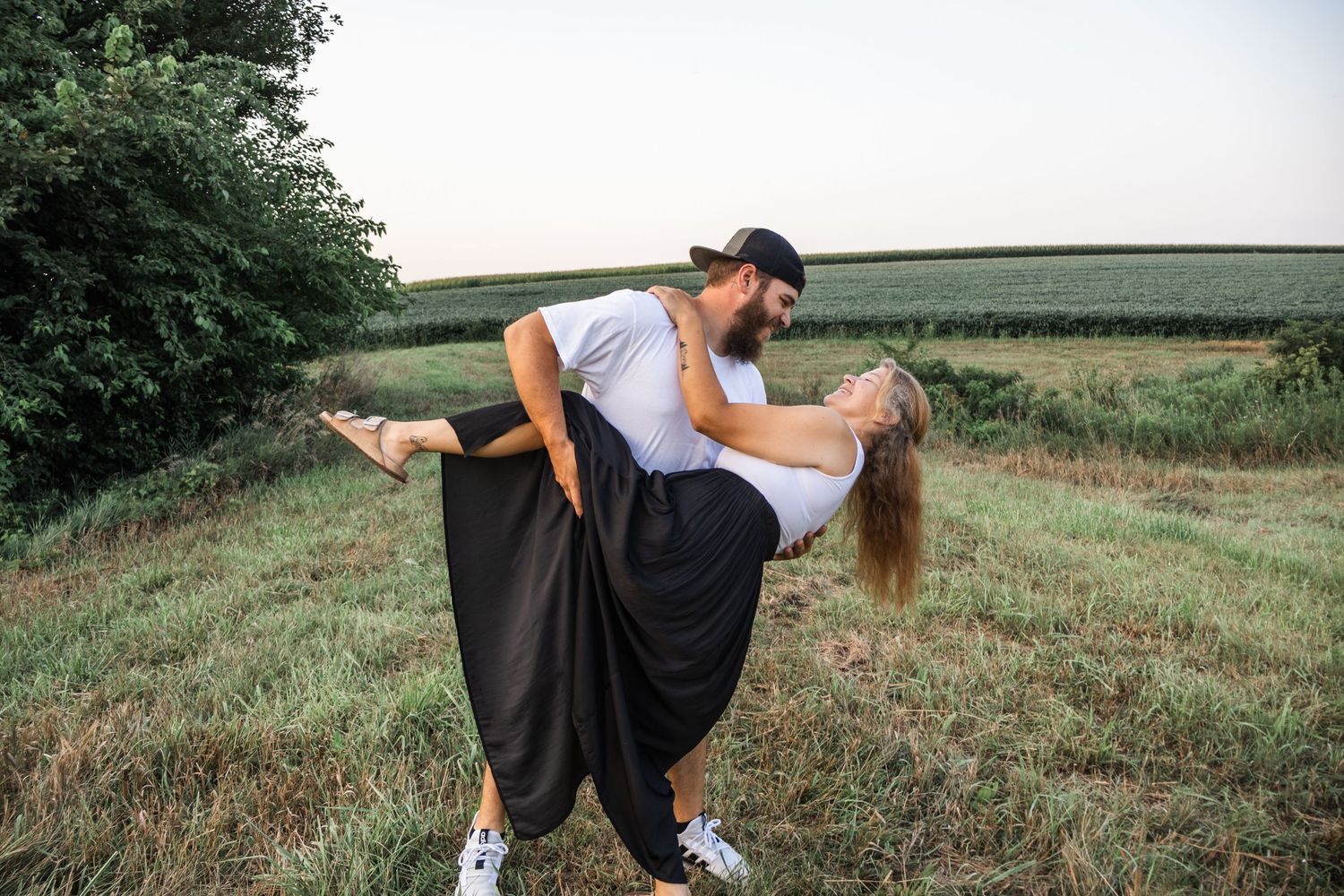 A romantic couple shares tender moments in a sunlit field during a photo session.