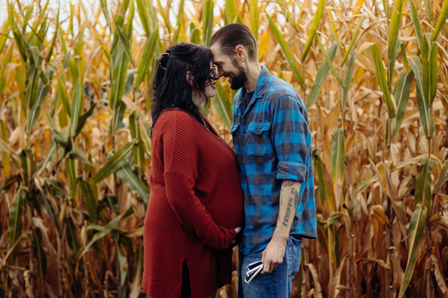 Couple walking and laughing together along a corn field path.