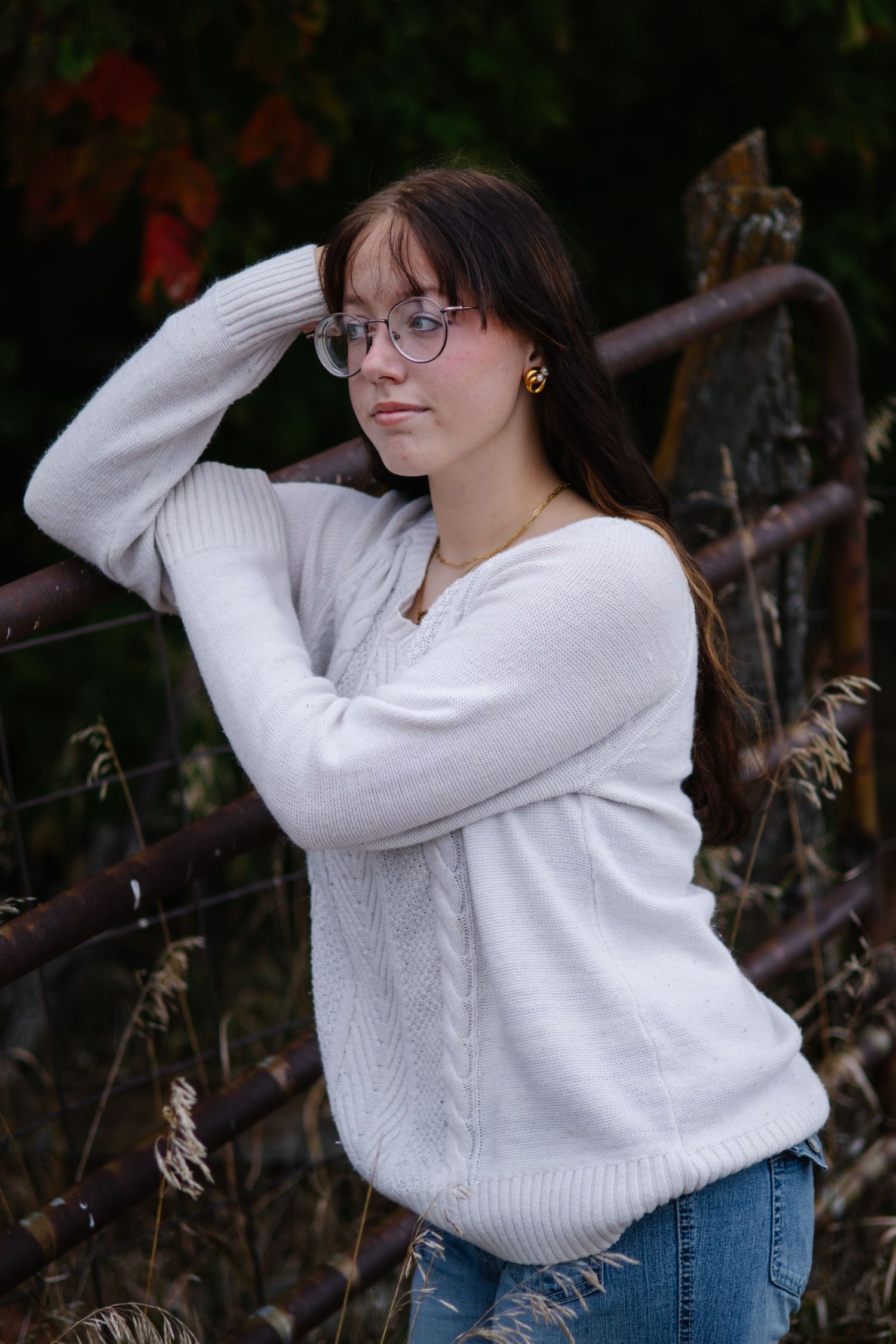Person in white sweater poses against dark foliage in multiple artistic shots.