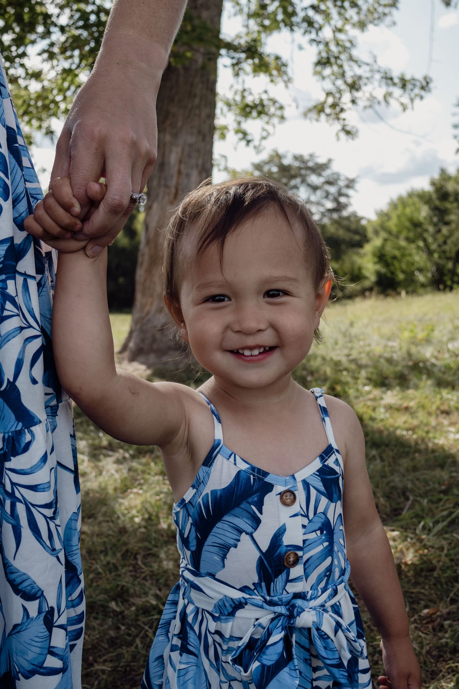 A sequence showing someone in a blue floral dress playing in a sunny garden setting.