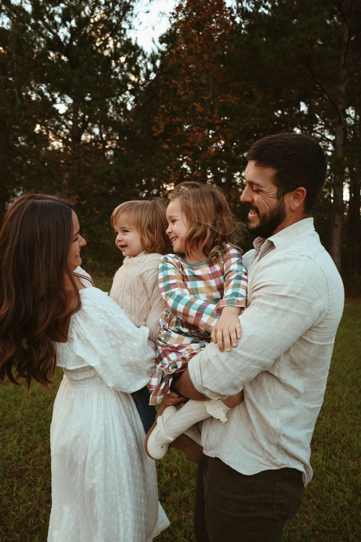 A family in white clothing shares playful moments together in a series of candid outdoor photos at sunset.