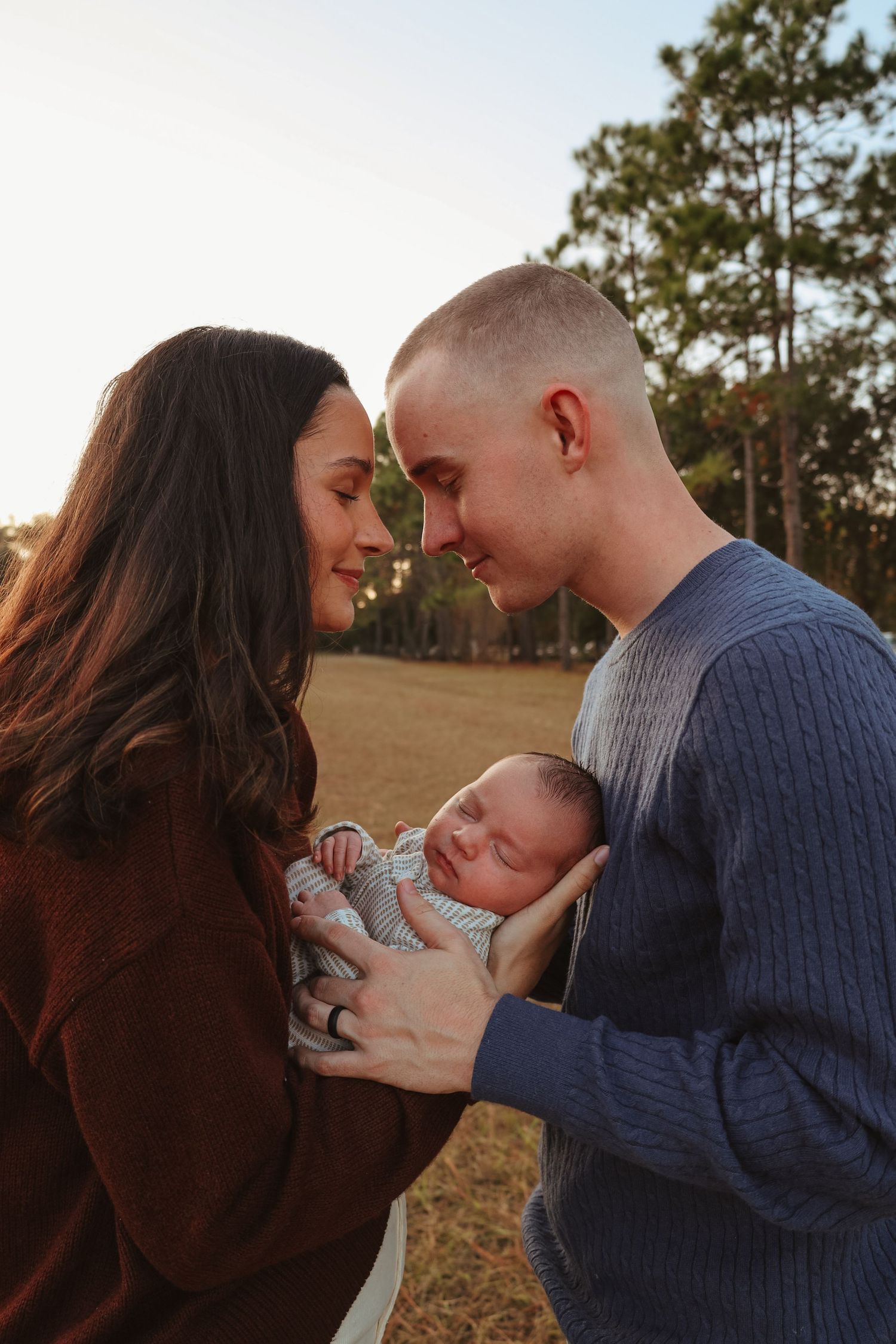 A loving family moment captured in a series of five intimate outdoor photos at sunset with their newborn baby.