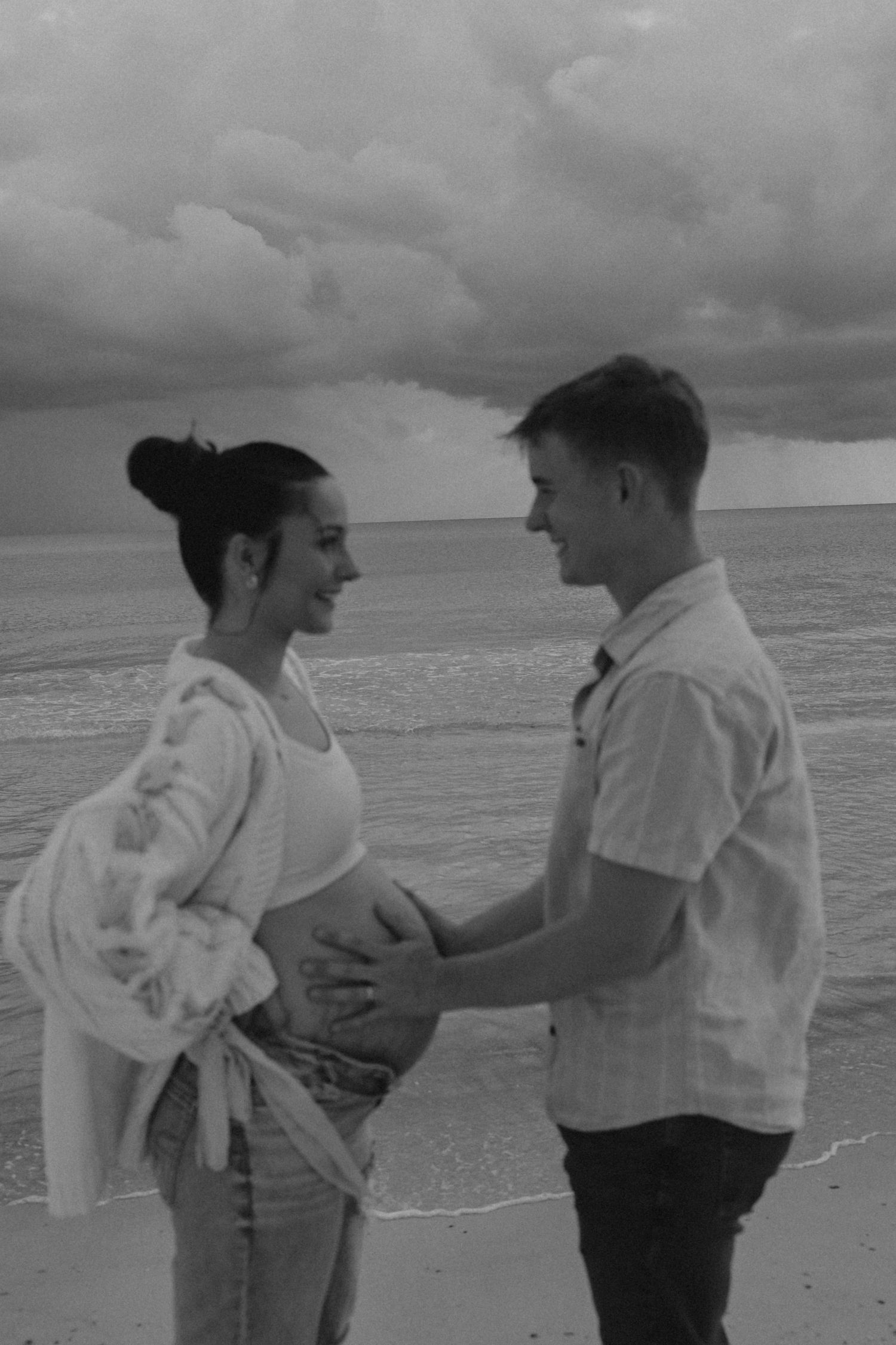 A romantic black and white photo sequence shows a couple embracing on a beach with waves and cloudy skies in the background.
