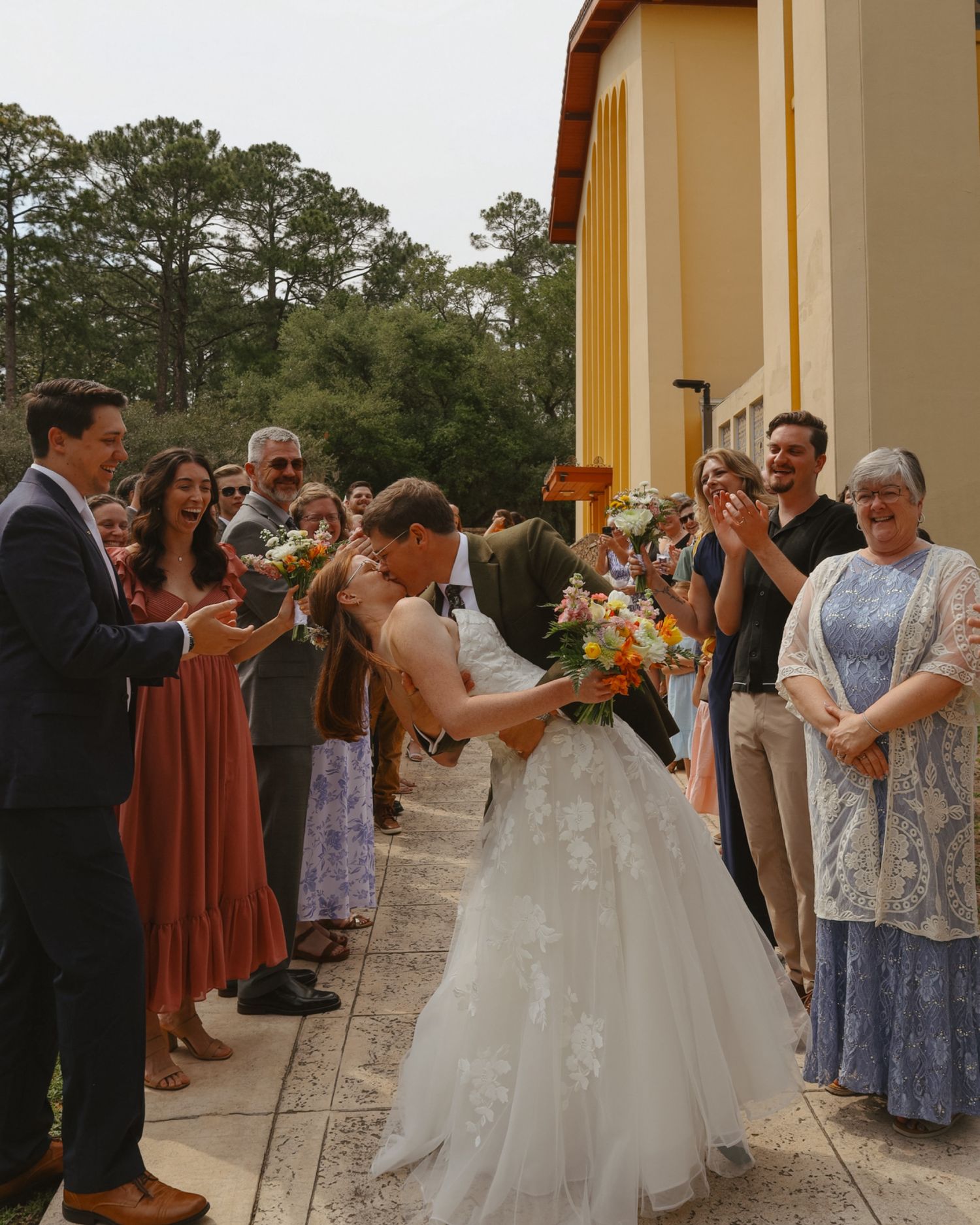 Wedding guests gather to celebrate and watch a couple's first dance at an outdoor venue.