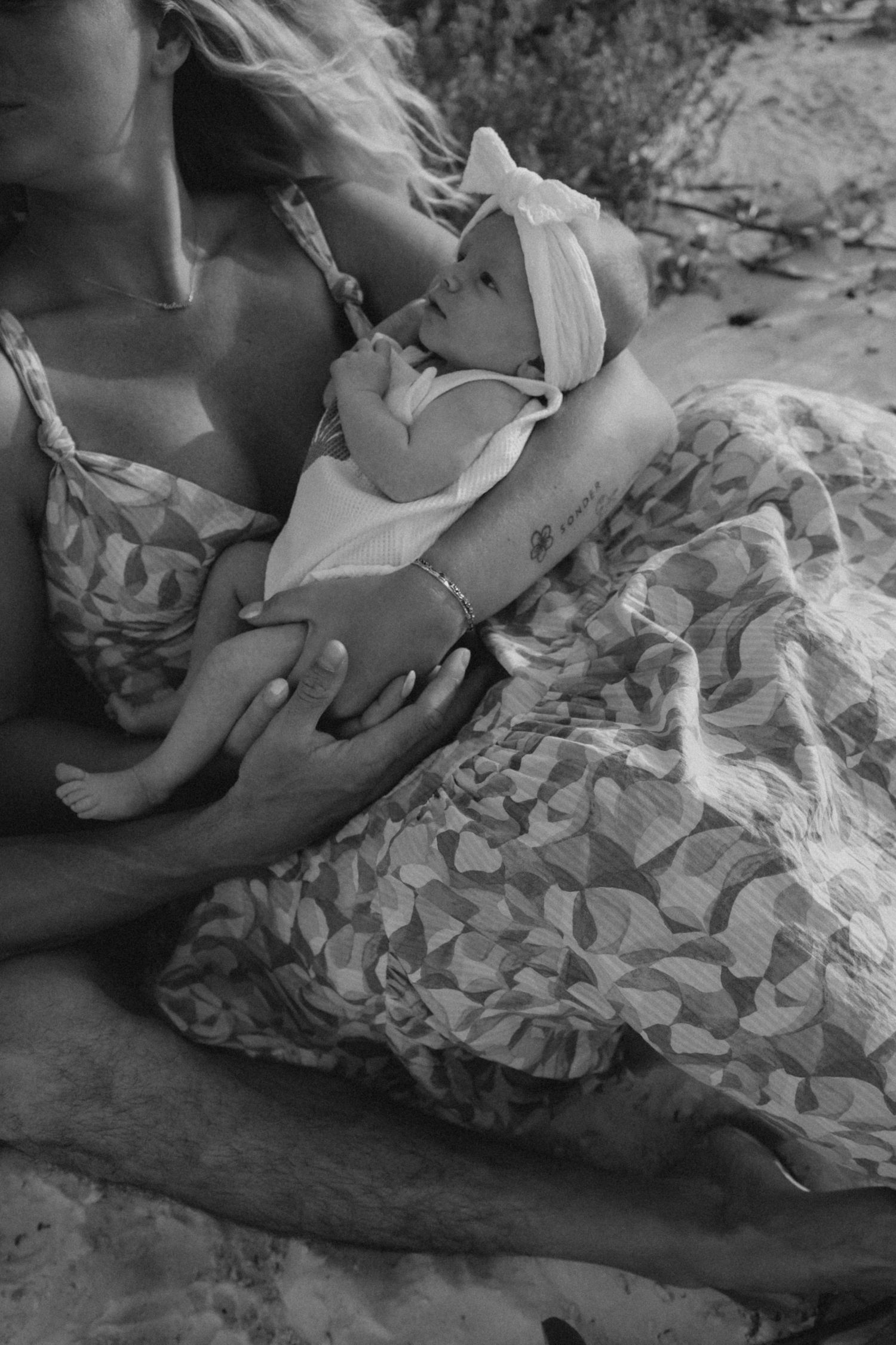 A tender black and white photograph of a parent and baby lying together in soft focus.