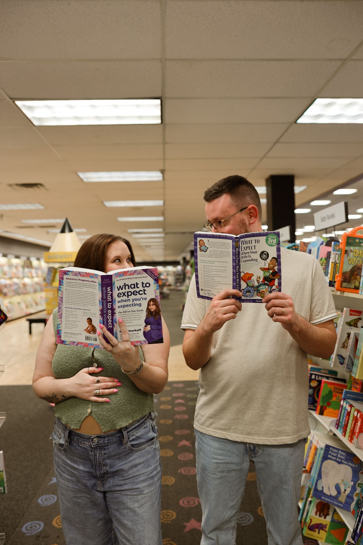 Couple reading 'What to Expect When Expecting' books in a bookstore, suggesting a pregnancy announcement.