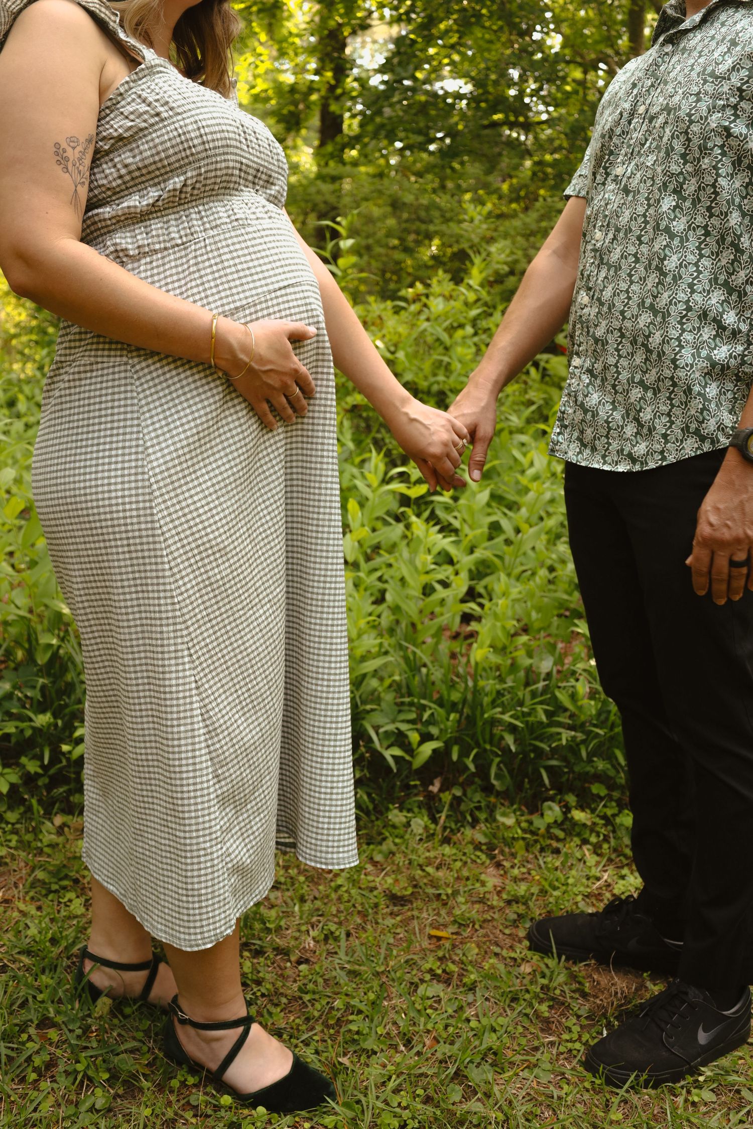 Close-up shot of couple's feet holding hands during engagement photos in a garden setting.