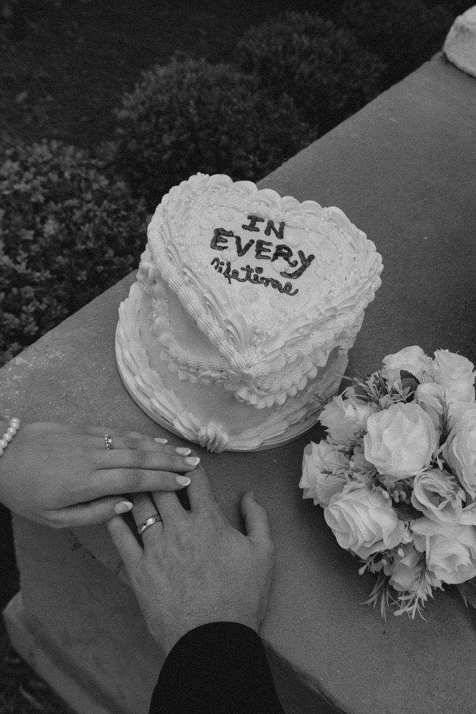 Black and white photo of heart-shaped wedding cakes decorated with white frosting and flowers on a table.