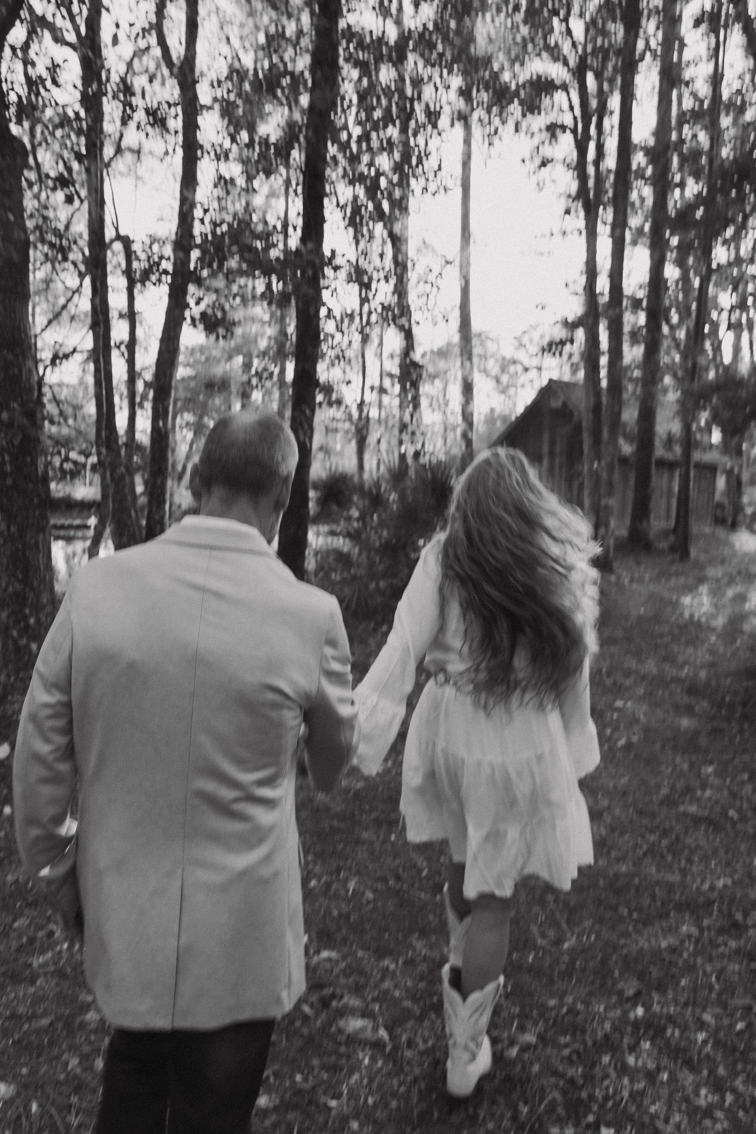 A black and white photo series shows a couple walking away through a wooded forest path.