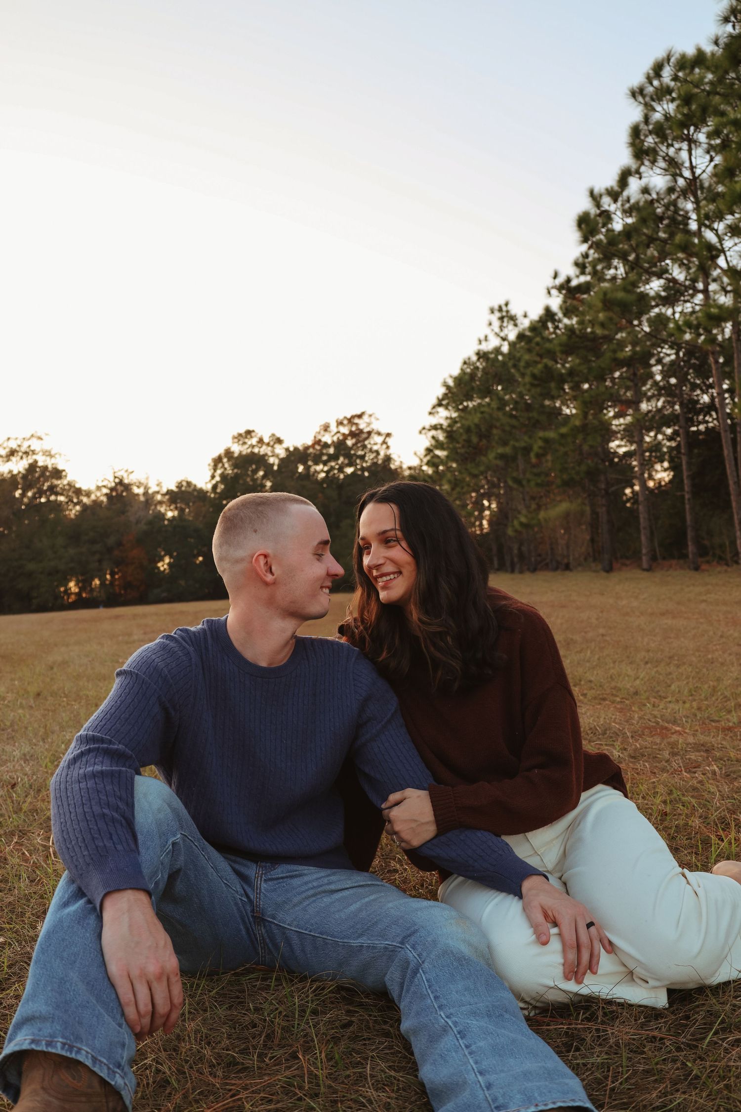 A couple lies together on grass during sunset sharing intimate moments in a series of connected photos.