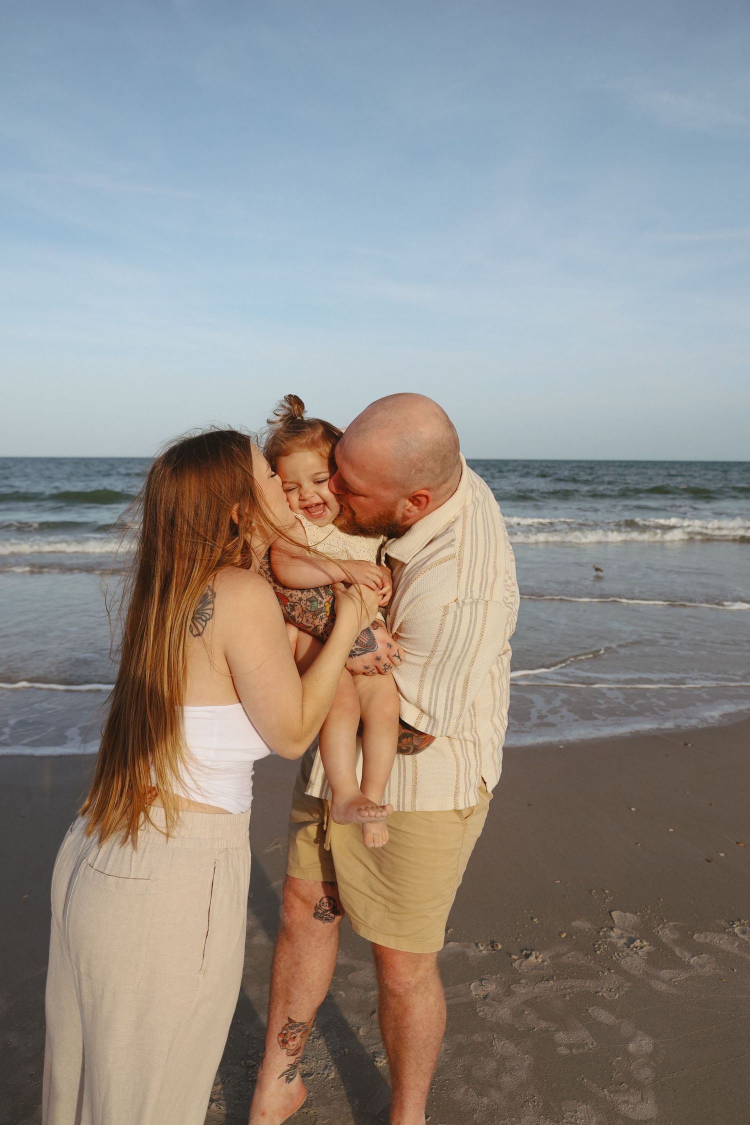 Family shares joyful moments together during sunset beach photoshoot.
