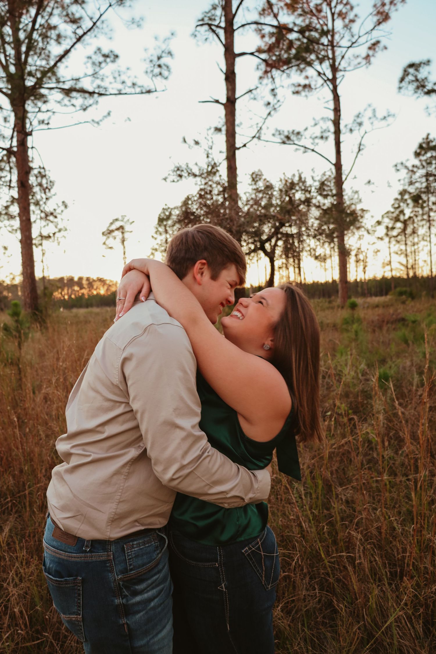 A romantic couple shares intimate moments in a golden field of tall grass at sunset.