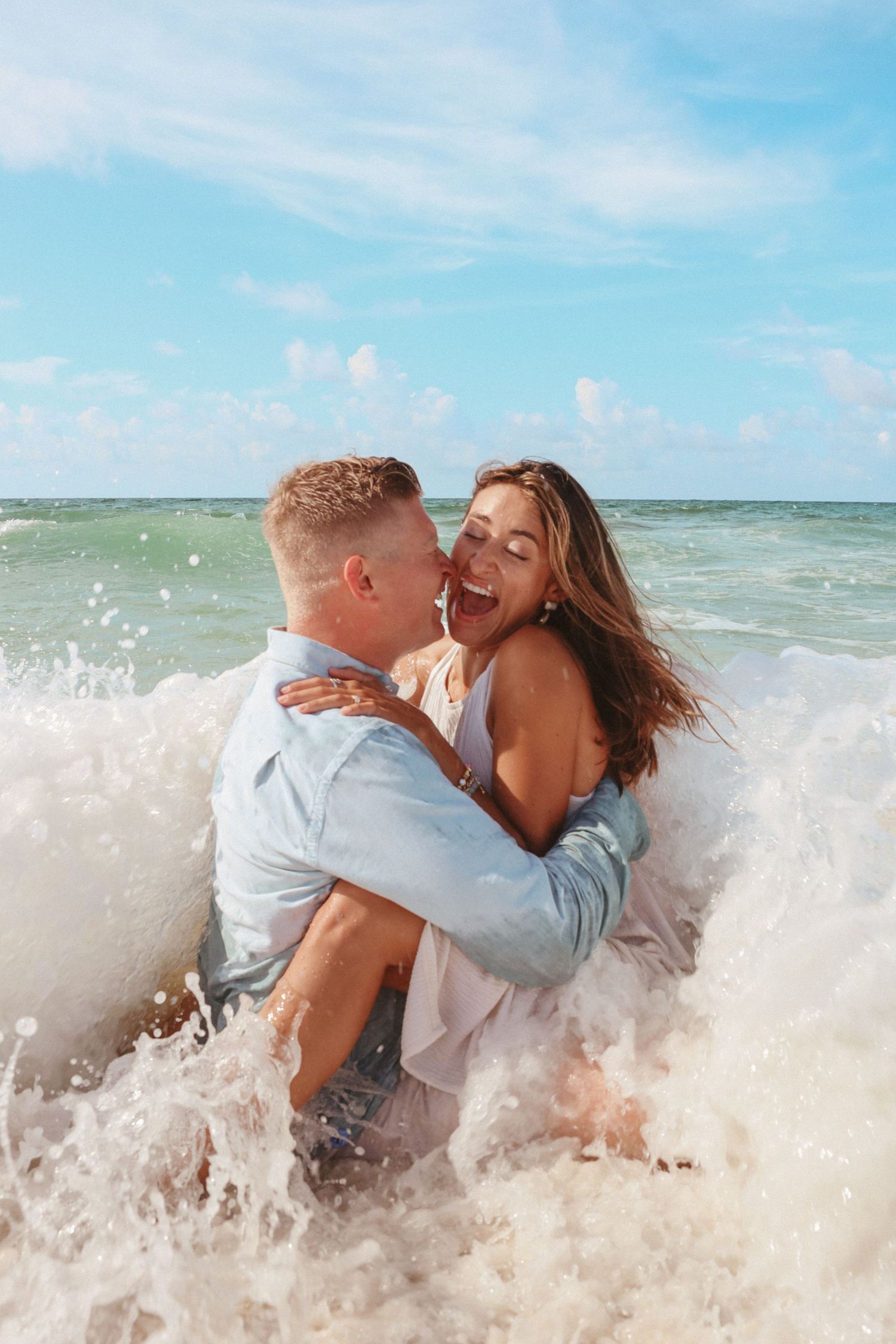 A joyful couple embracing in the ocean waves on a bright sunny day.