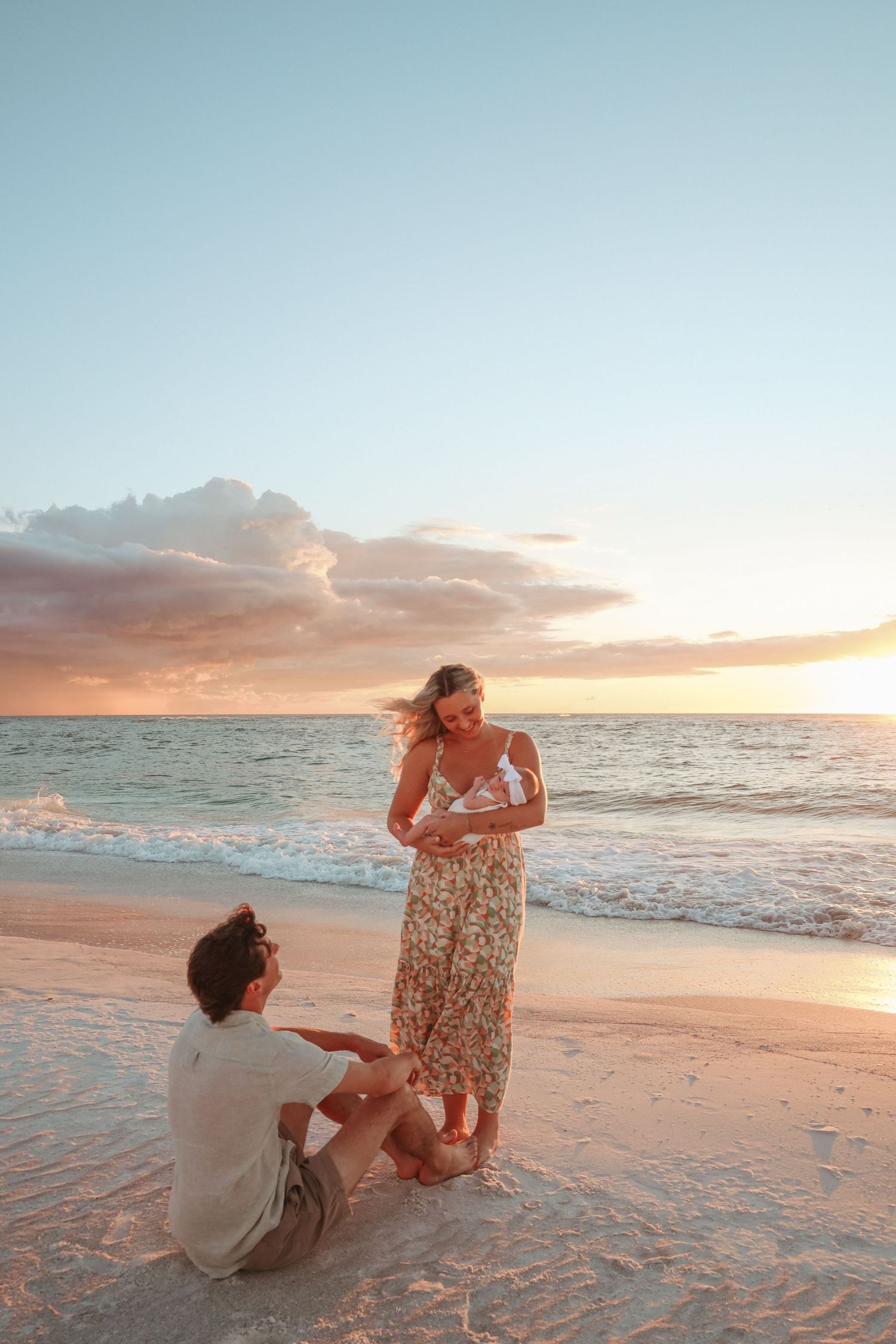 A romantic beach proposal scene unfolds during golden hour as waves roll onto the sandy shore.