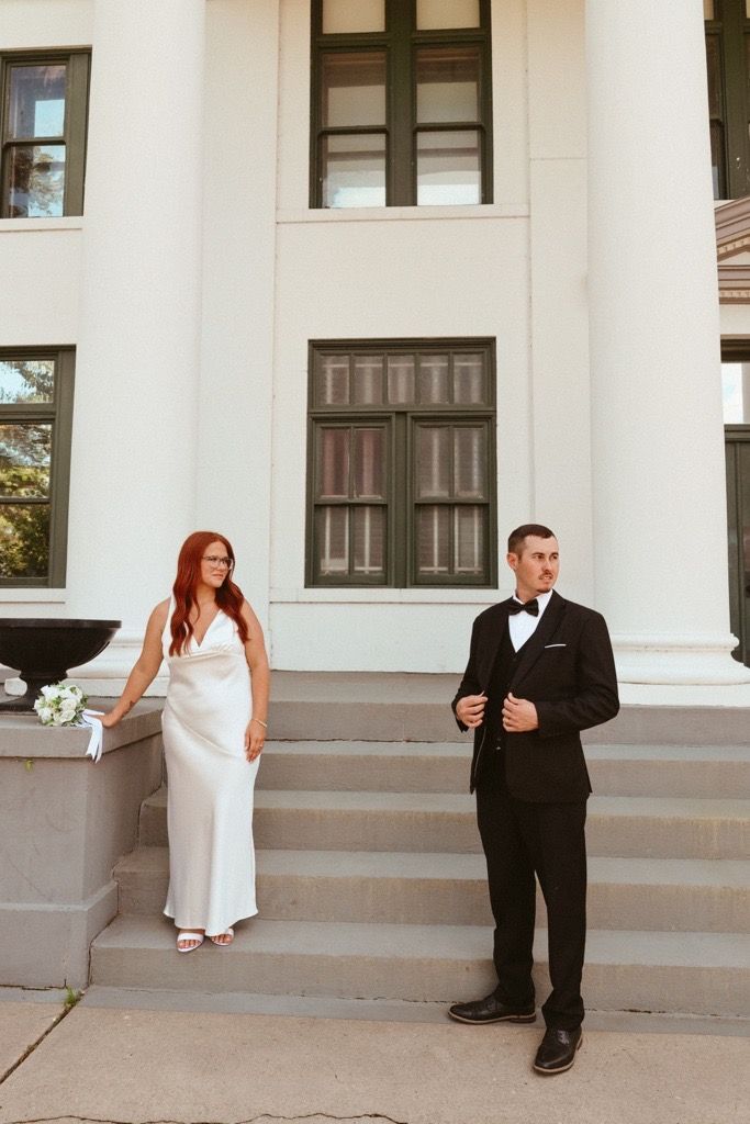 A bride in white and groom in black suit pose playfully on building steps in a series of candid wedding photos.