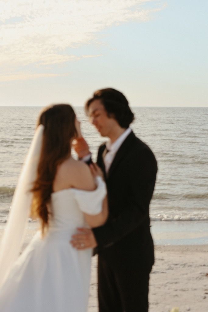 A romantic beach wedding ceremony silhouette sequence showing a couple kissing at sunset by the ocean.