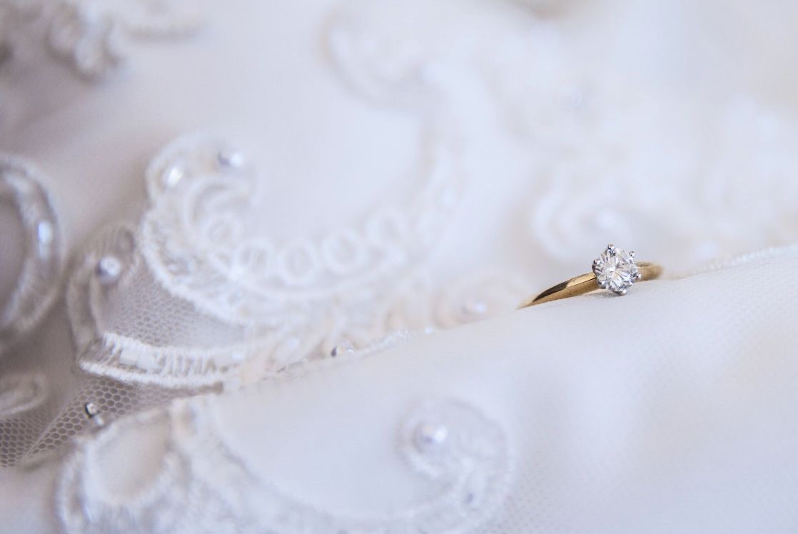 Macro shot of sparkling diamond engagement ring with delicate lace details.