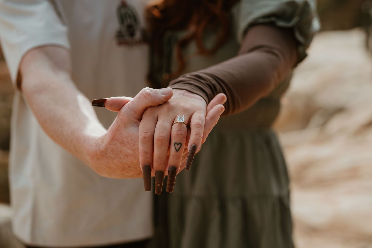 Close-up of hands with delicate rings against neutral background.