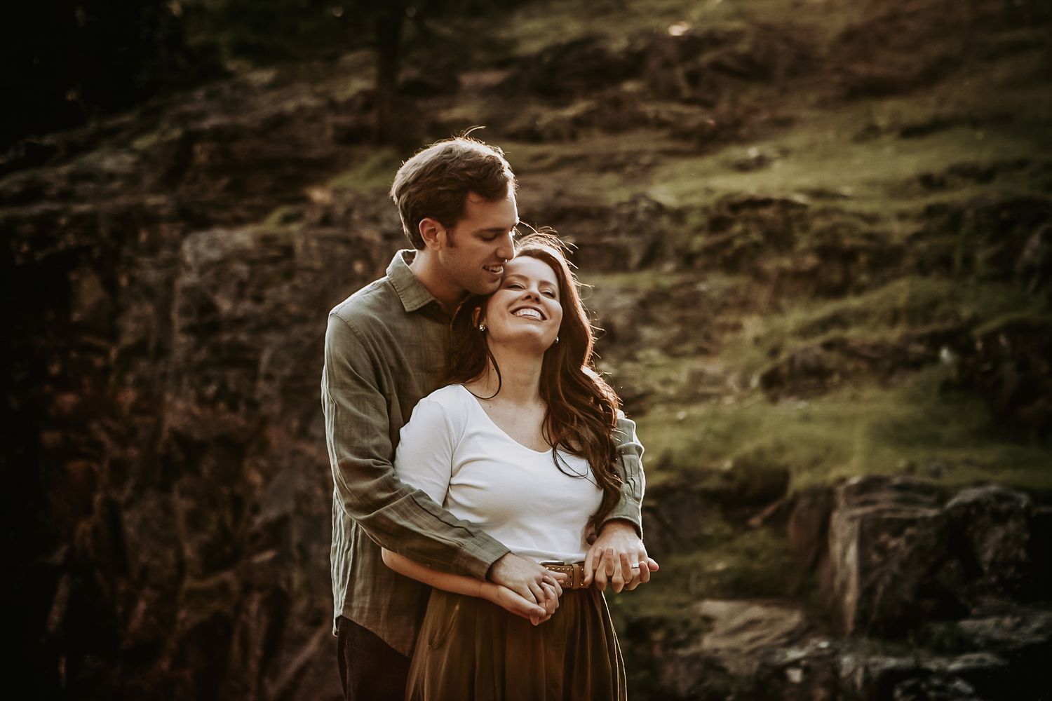 A romantic sunset photoshoot on a windswept cliff with dramatic lighting.