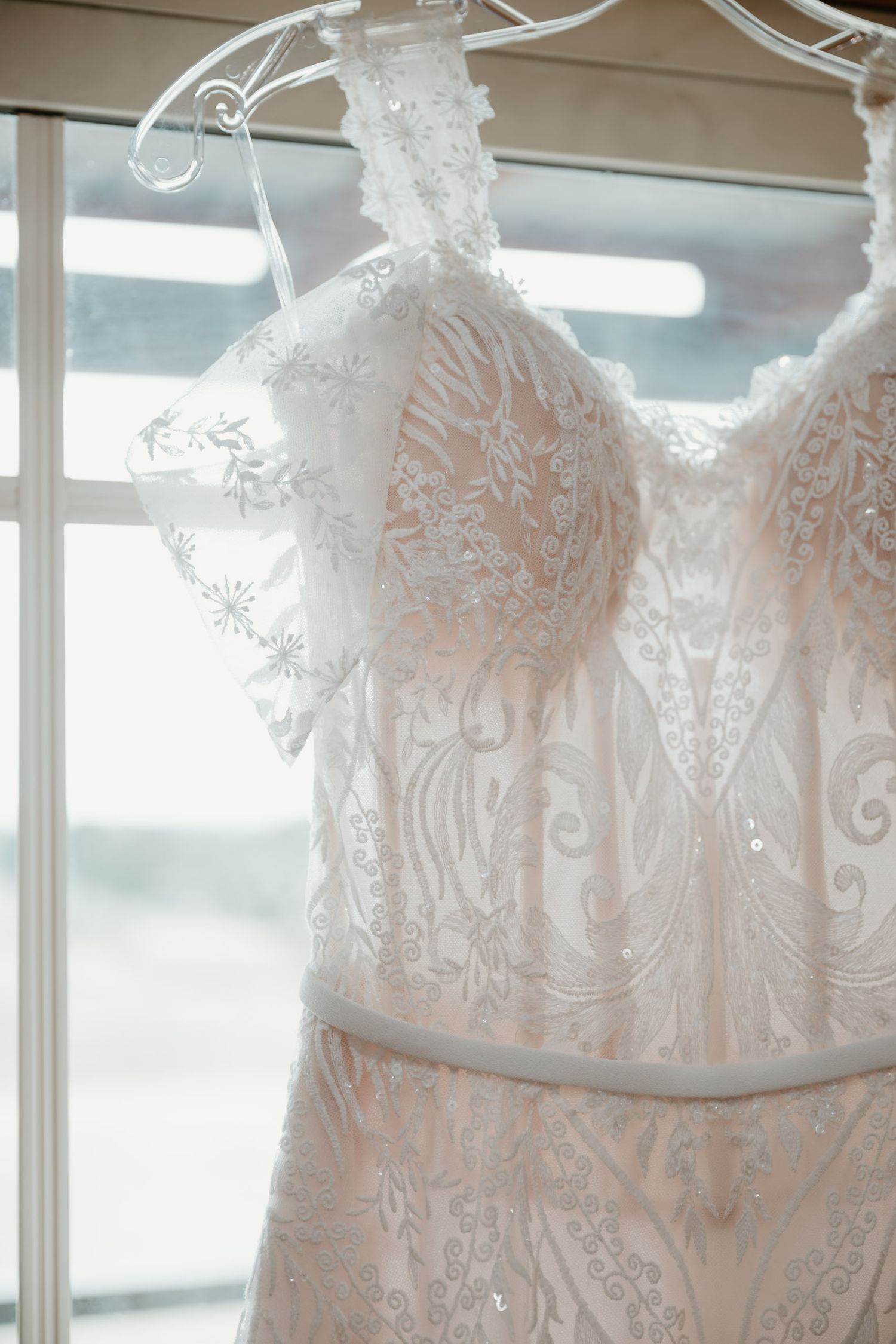 Close up of intricate lace details on hanging wedding dress bodice.