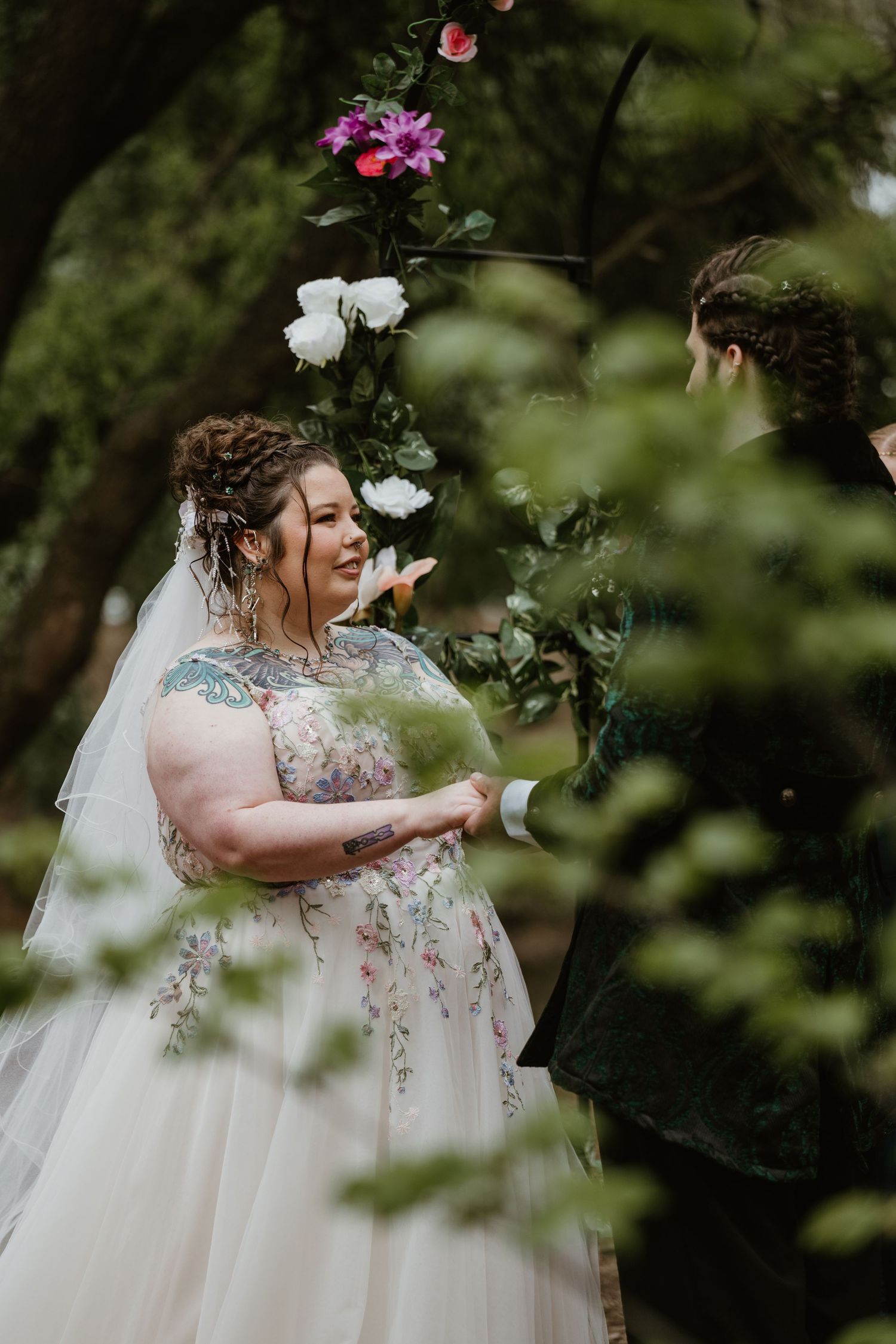 A romantic outdoor wedding photoshoot featuring a bride in a flowing white dress with floral embellishments.