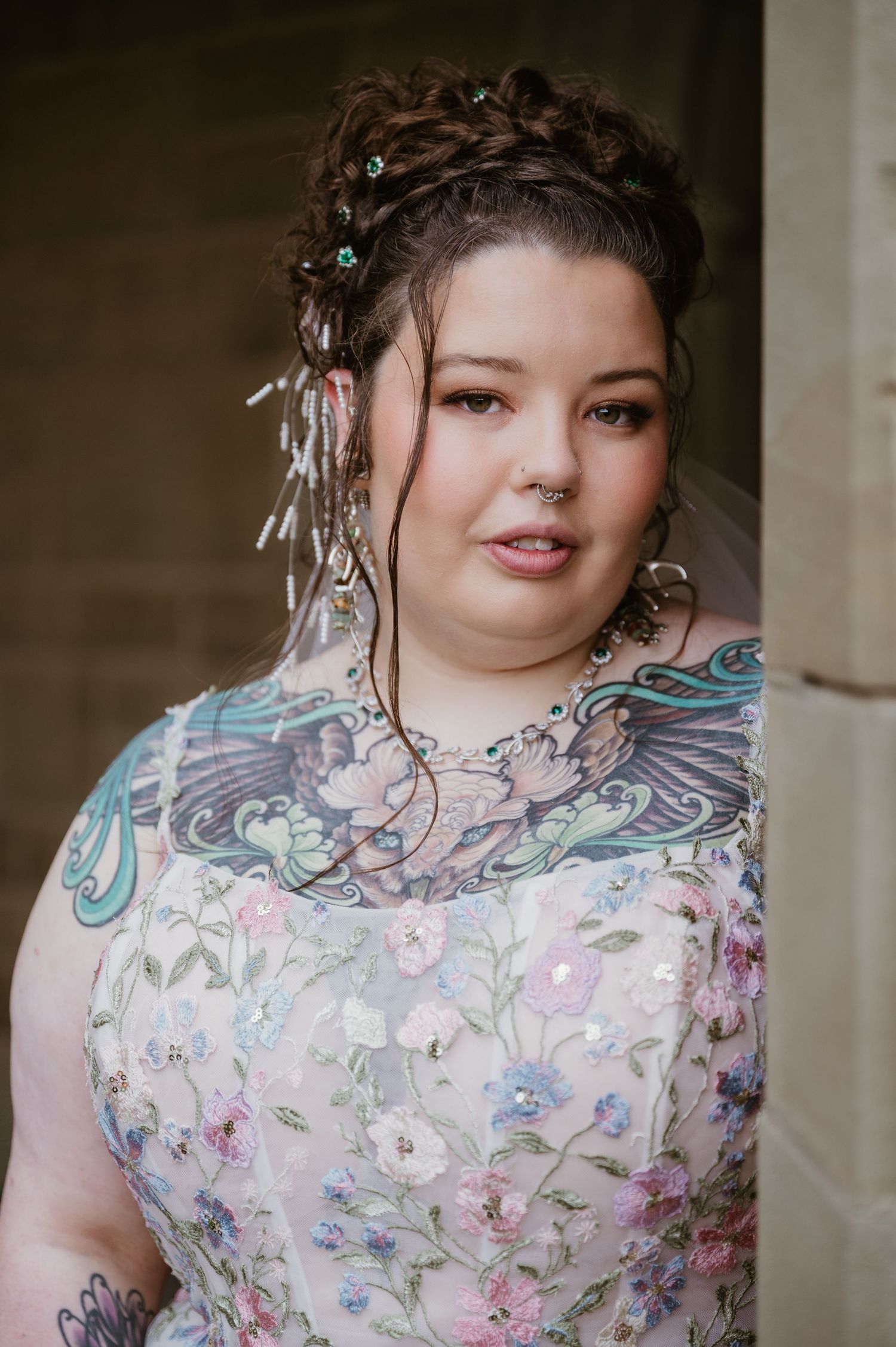 Floral dress with intricate hairstyle adorned with pearls and sparkly hair accessories against neutral backdrop.