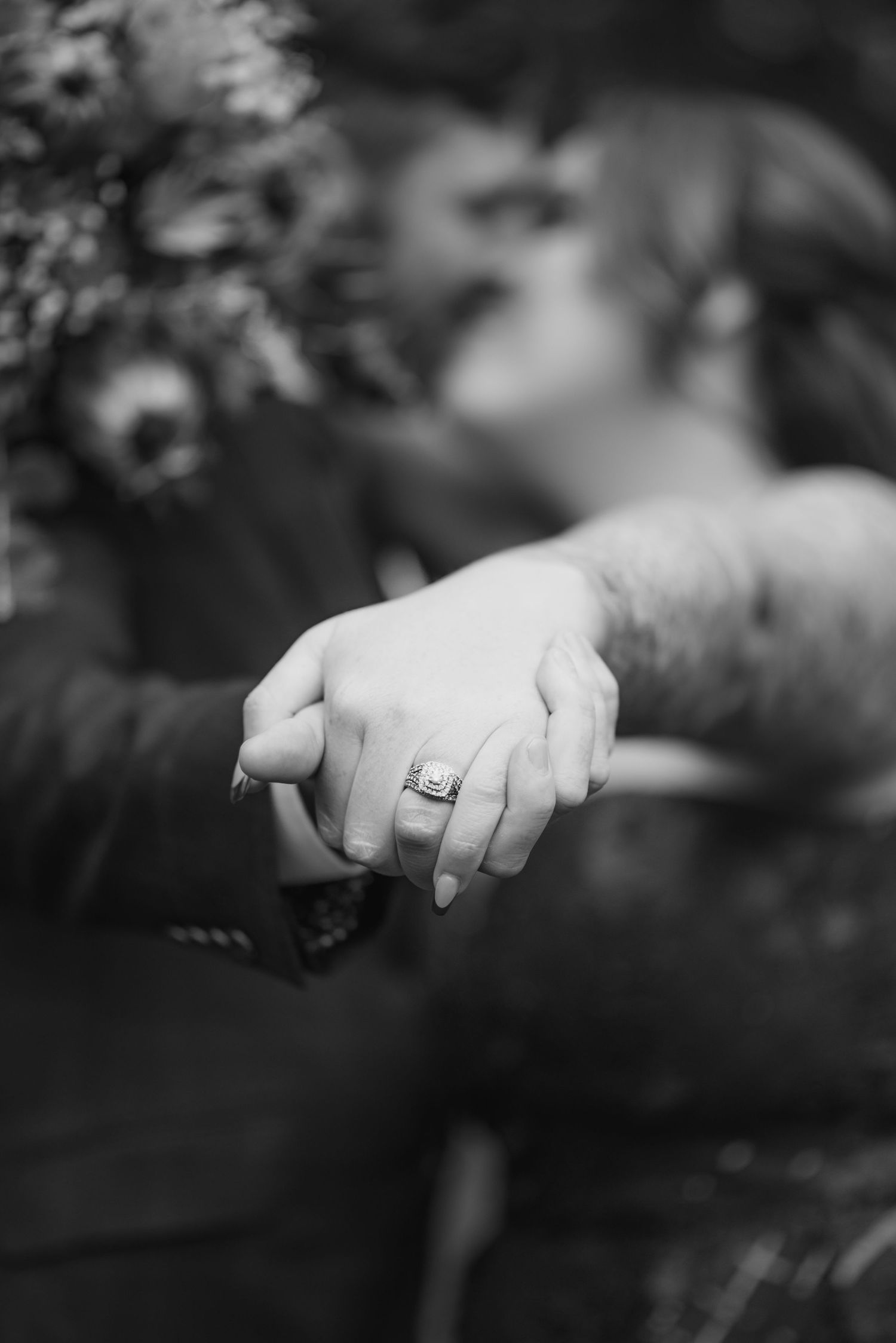 Black and white close-up of hands with wedding rings showing intimate details.