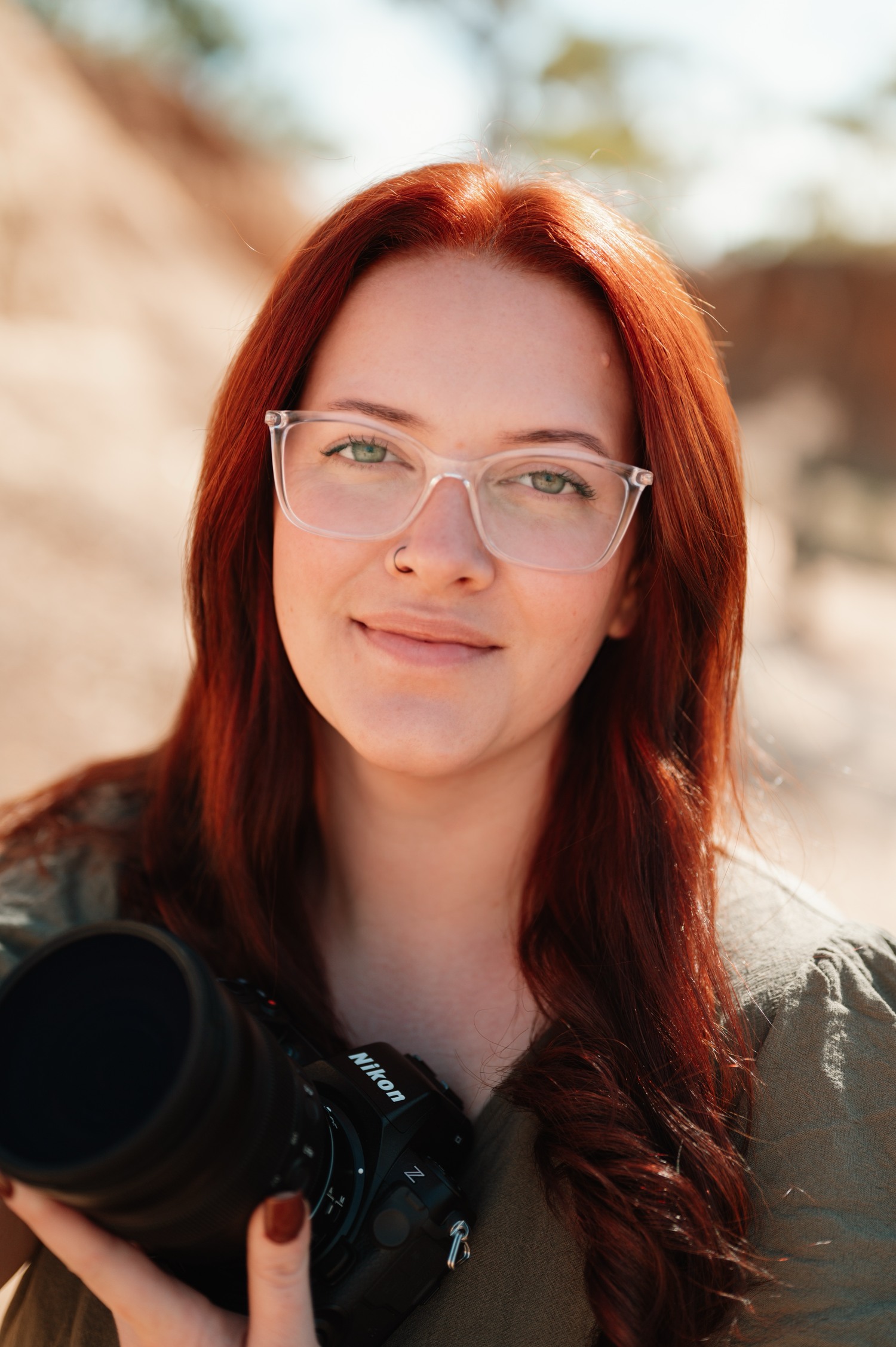 Portrait with vibrant red hair against warm sunlit background.