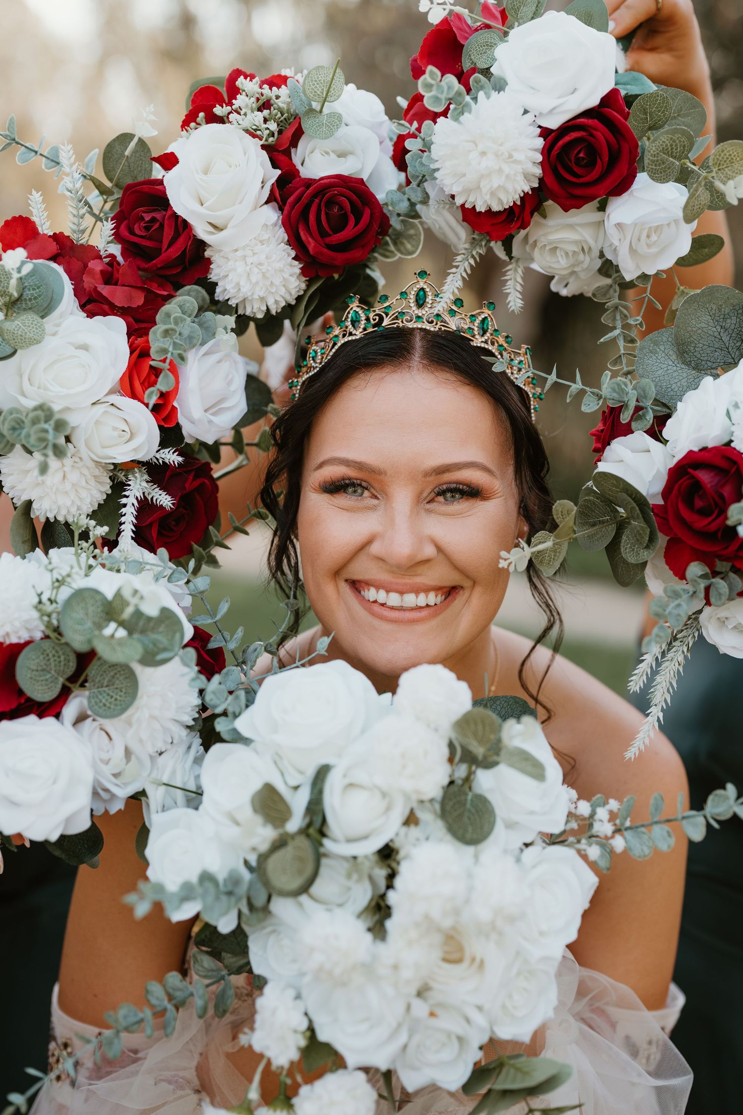 A stunning bridal bouquet features red and white roses with eucalyptus leaves.