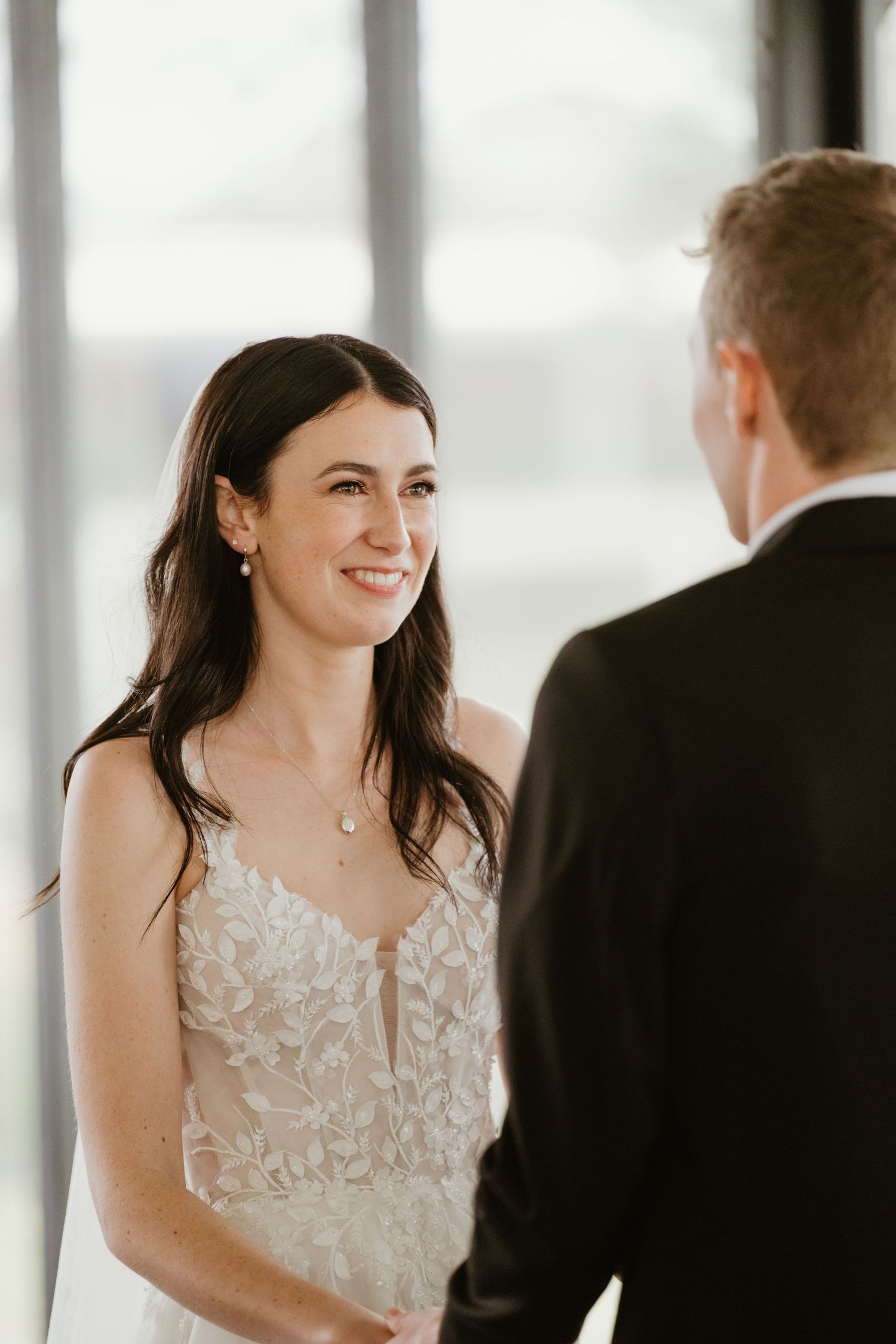 Candid moment during wedding ceremony with natural window lighting.