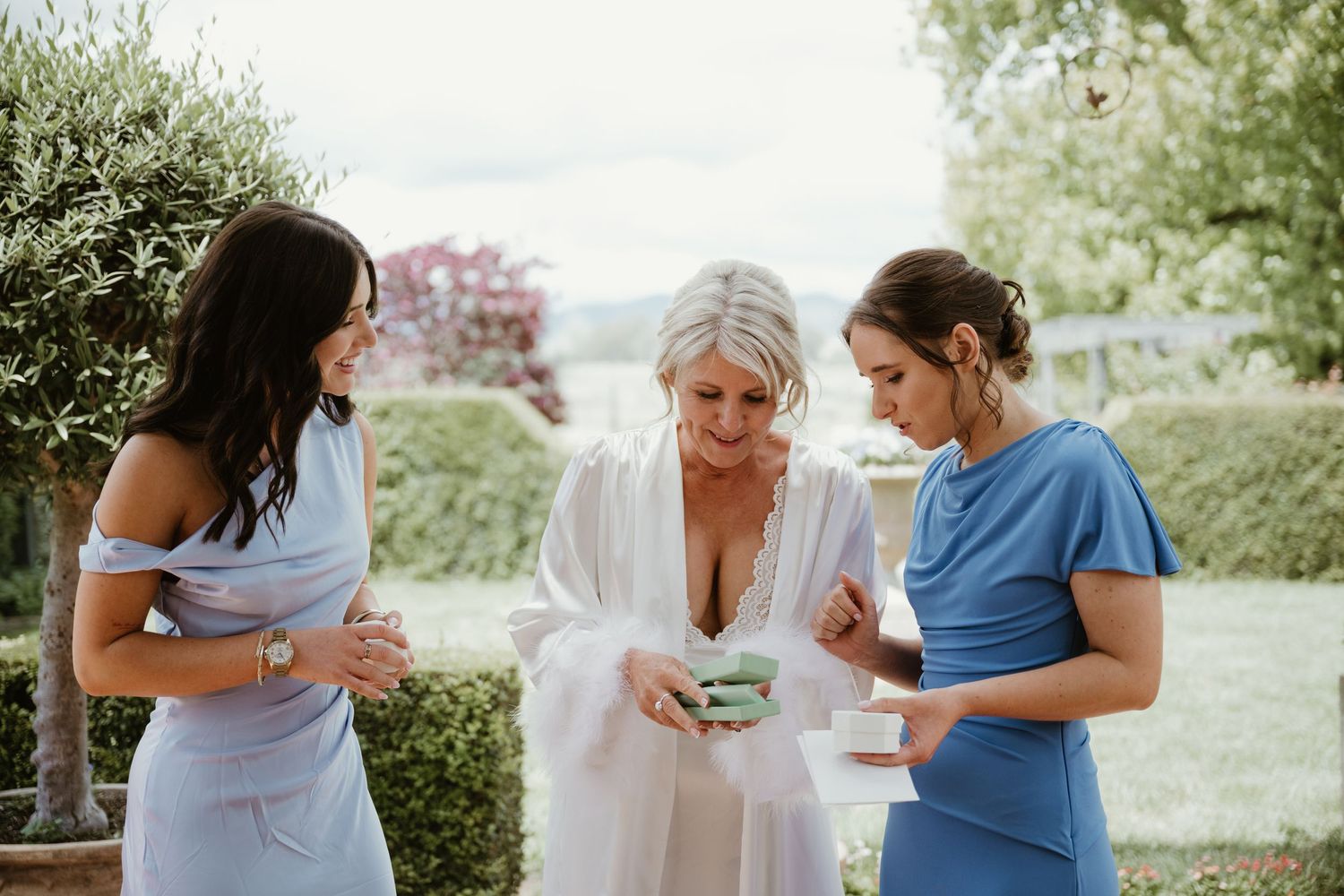 A group of people in blue and white dresses gather together outdoors in a garden setting.