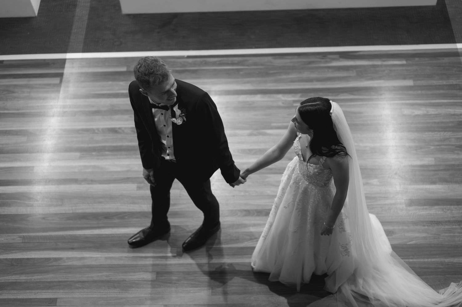 Black and white photo of couples dancing on a polished ballroom floor.