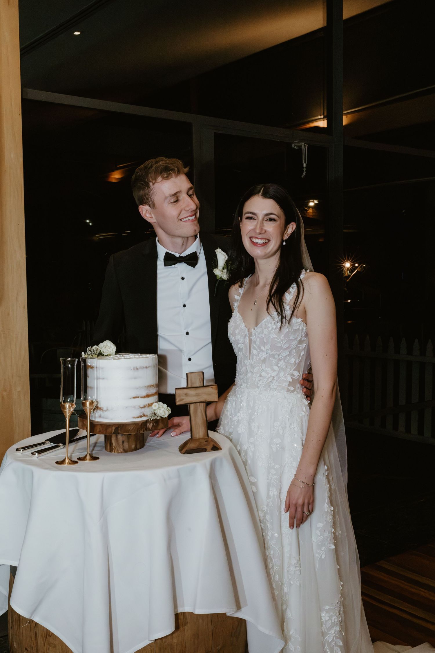 A wedding reception scene with elegant white tablecloths and a wedding cake display.