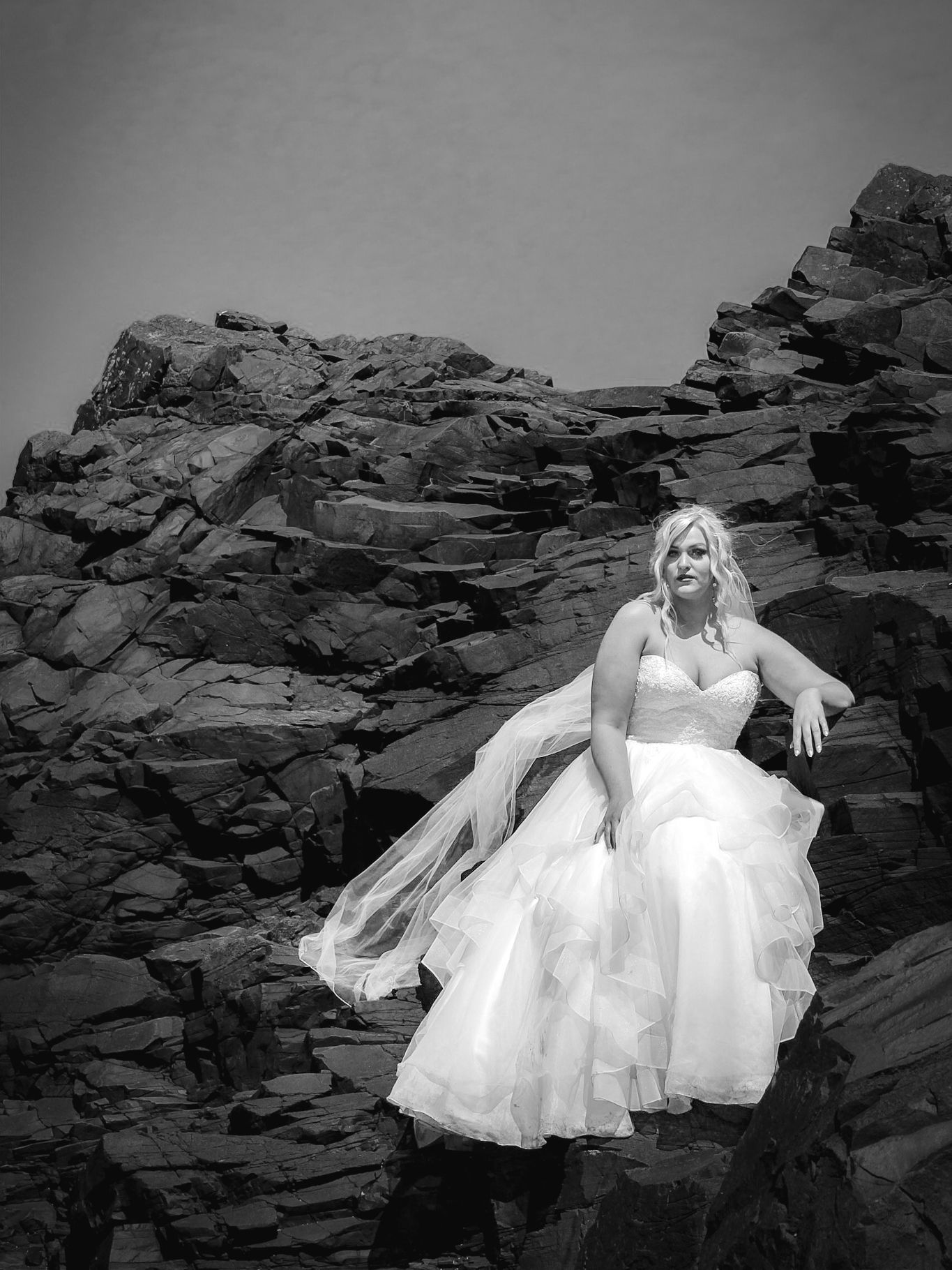 Dramatic black and white bridal portrait on rugged rocky terrain.