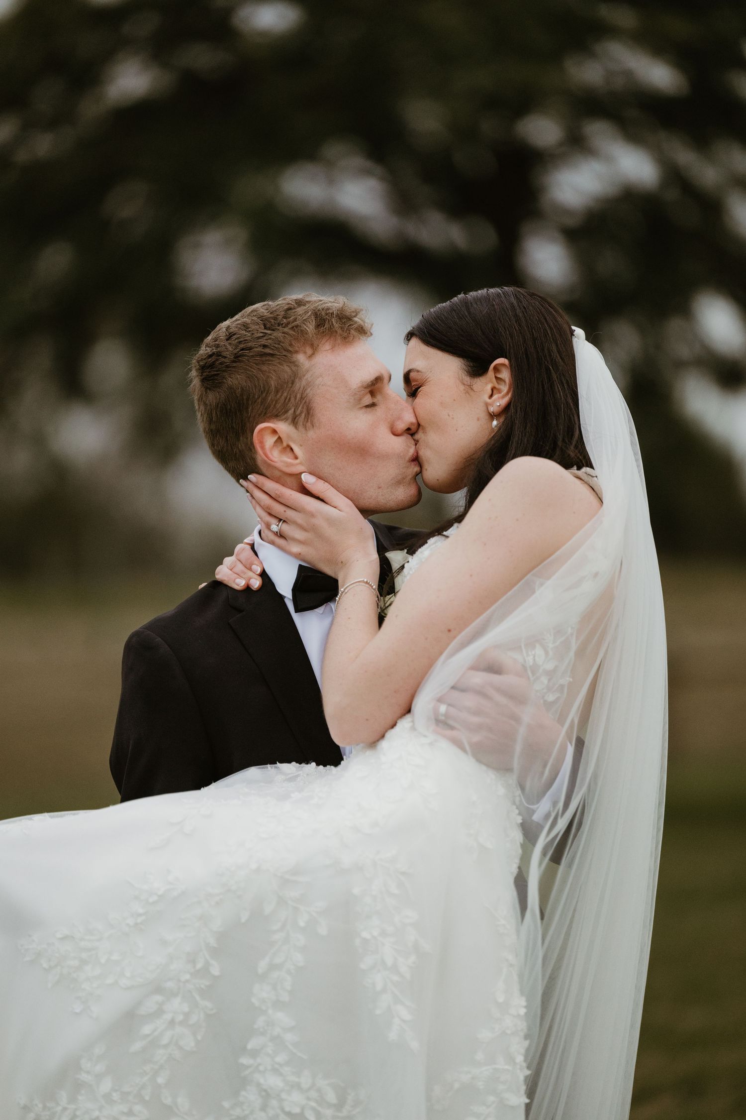 A tender wedding moment shared between newlyweds with the bride's veil flowing in the breeze.