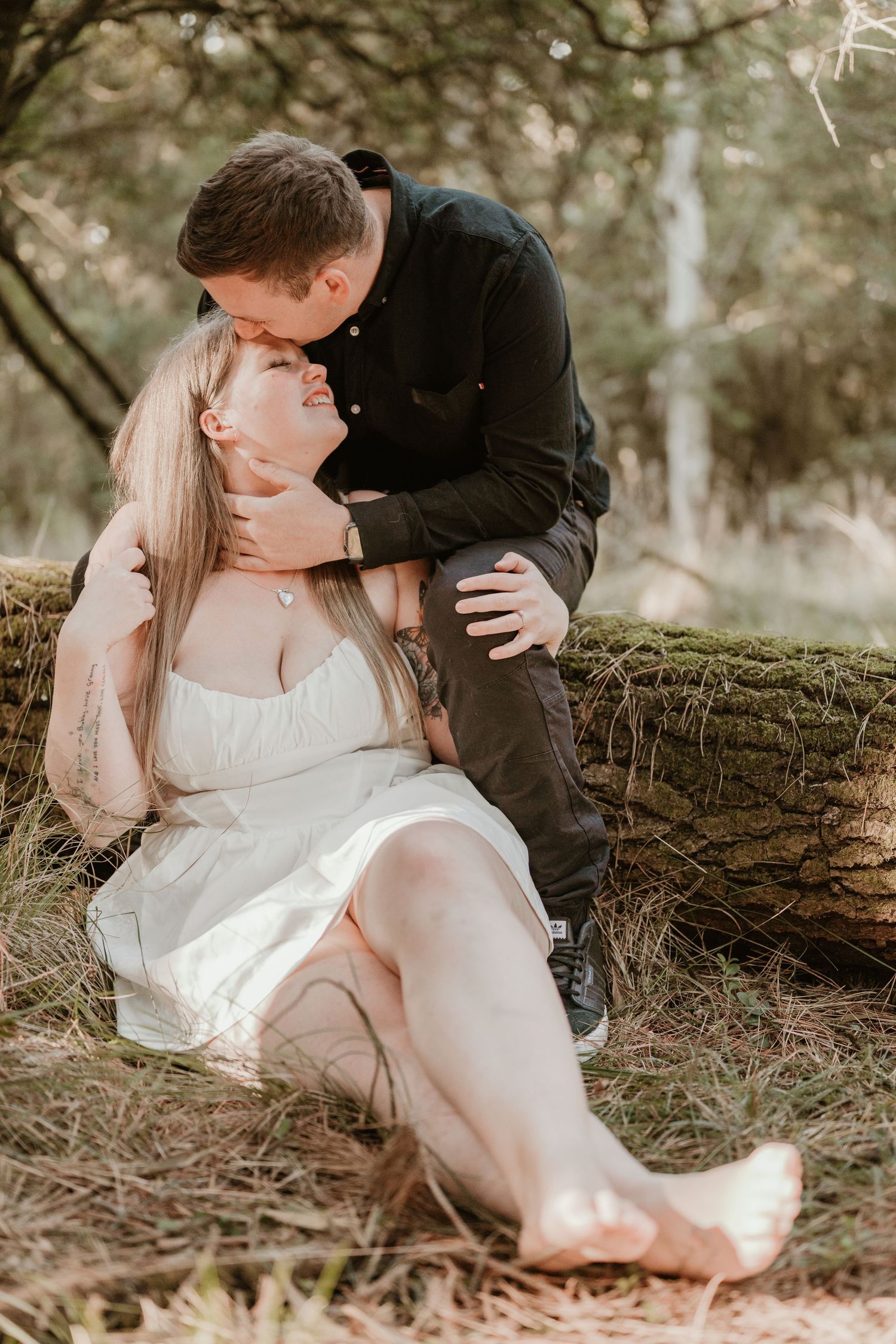 A romantic outdoor photoshoot in a natural wooded setting with soft lighting.