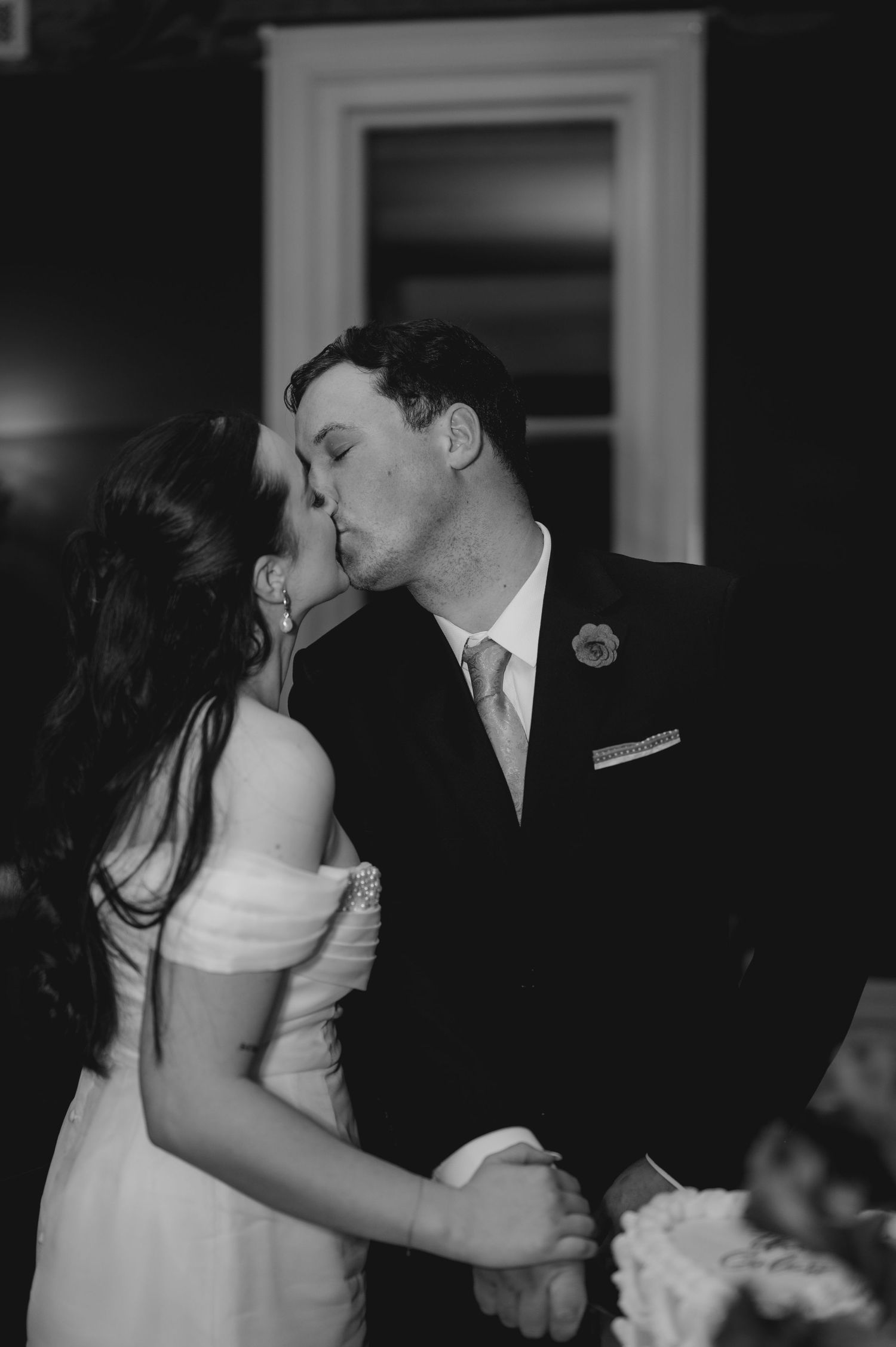 A romantic black and white photo sequence of a couple sharing a tender kiss at their wedding reception.