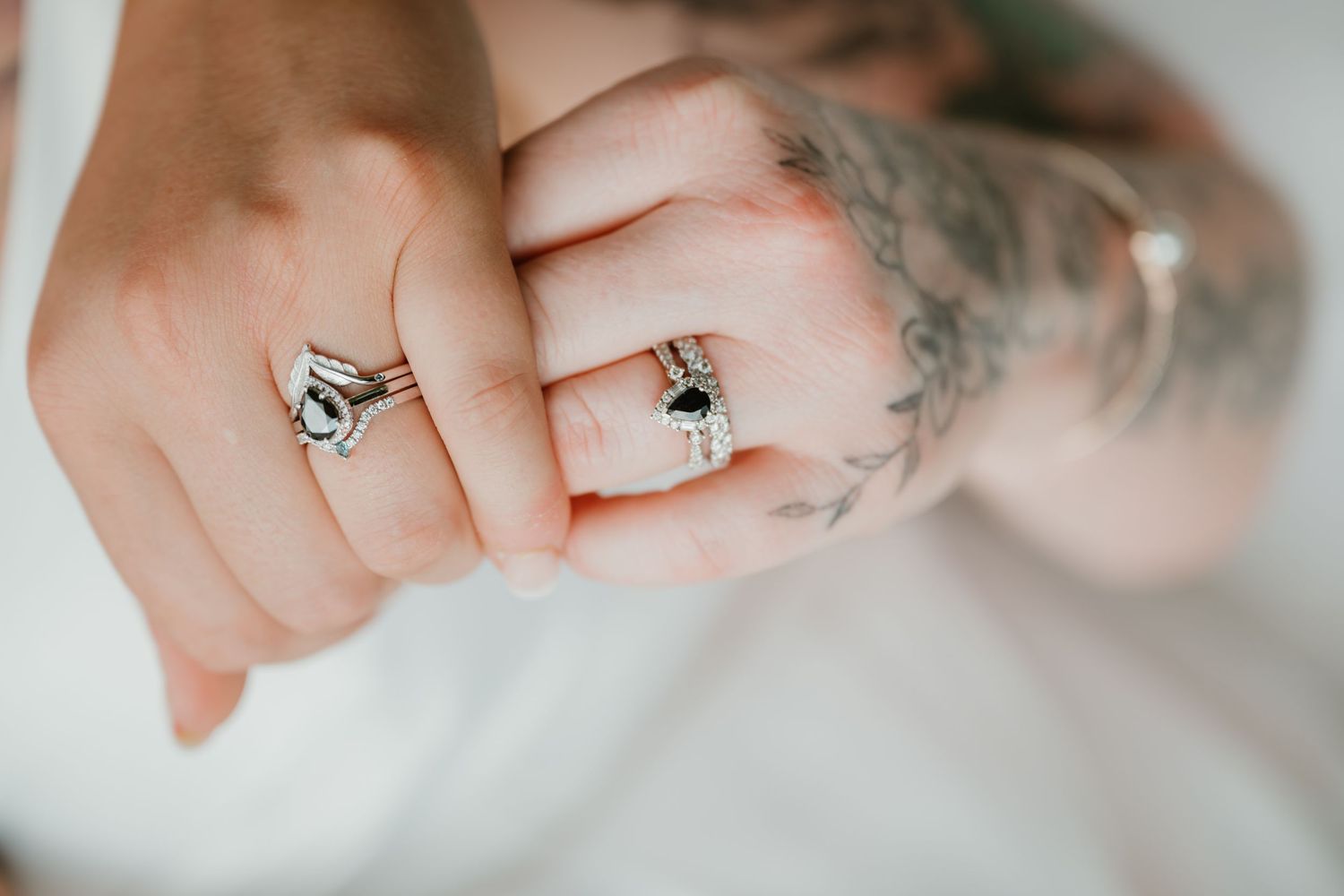 Detail shot of hands showing wedding rings with delicate tattoo artwork.