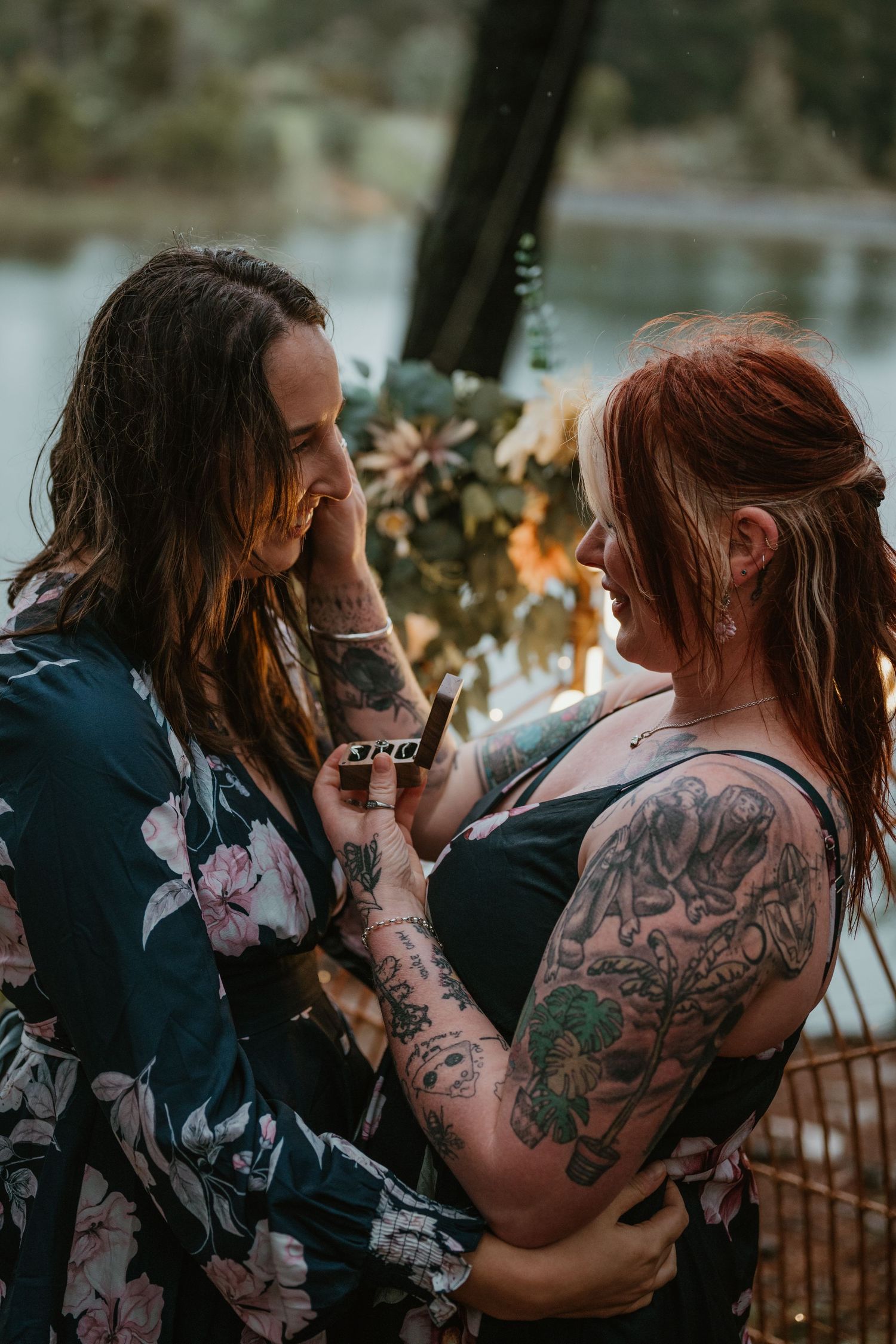 A romantic outdoor scene with floral dresses and decorated backdrop by the water.