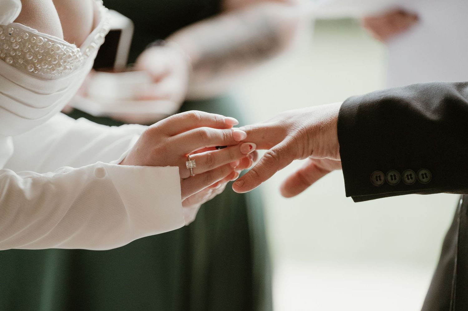 Close-up shot of hands exchanging wedding rings during a traditional marriage ceremony.