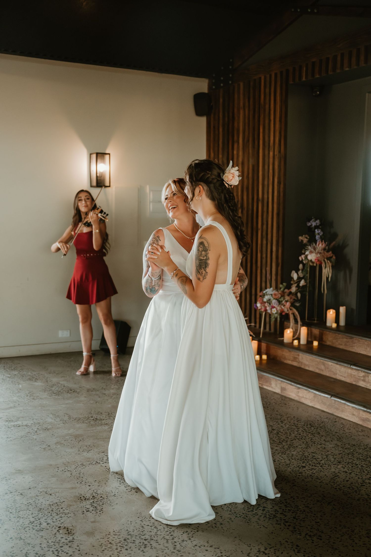Wedding celebration scene with white gowns and wooden wall details.