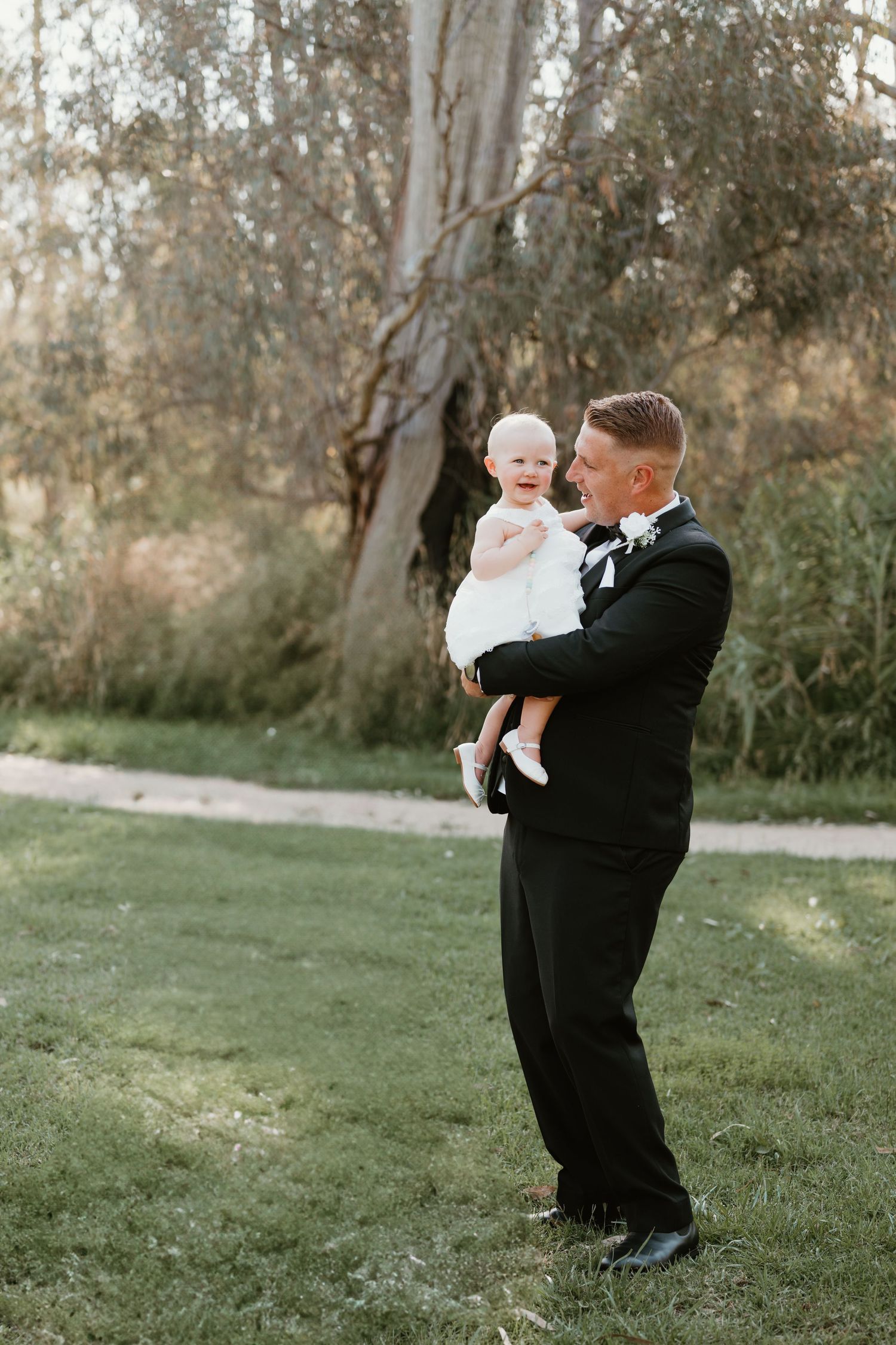 A touching moment between figures in formal attire on grassy outdoor grounds.