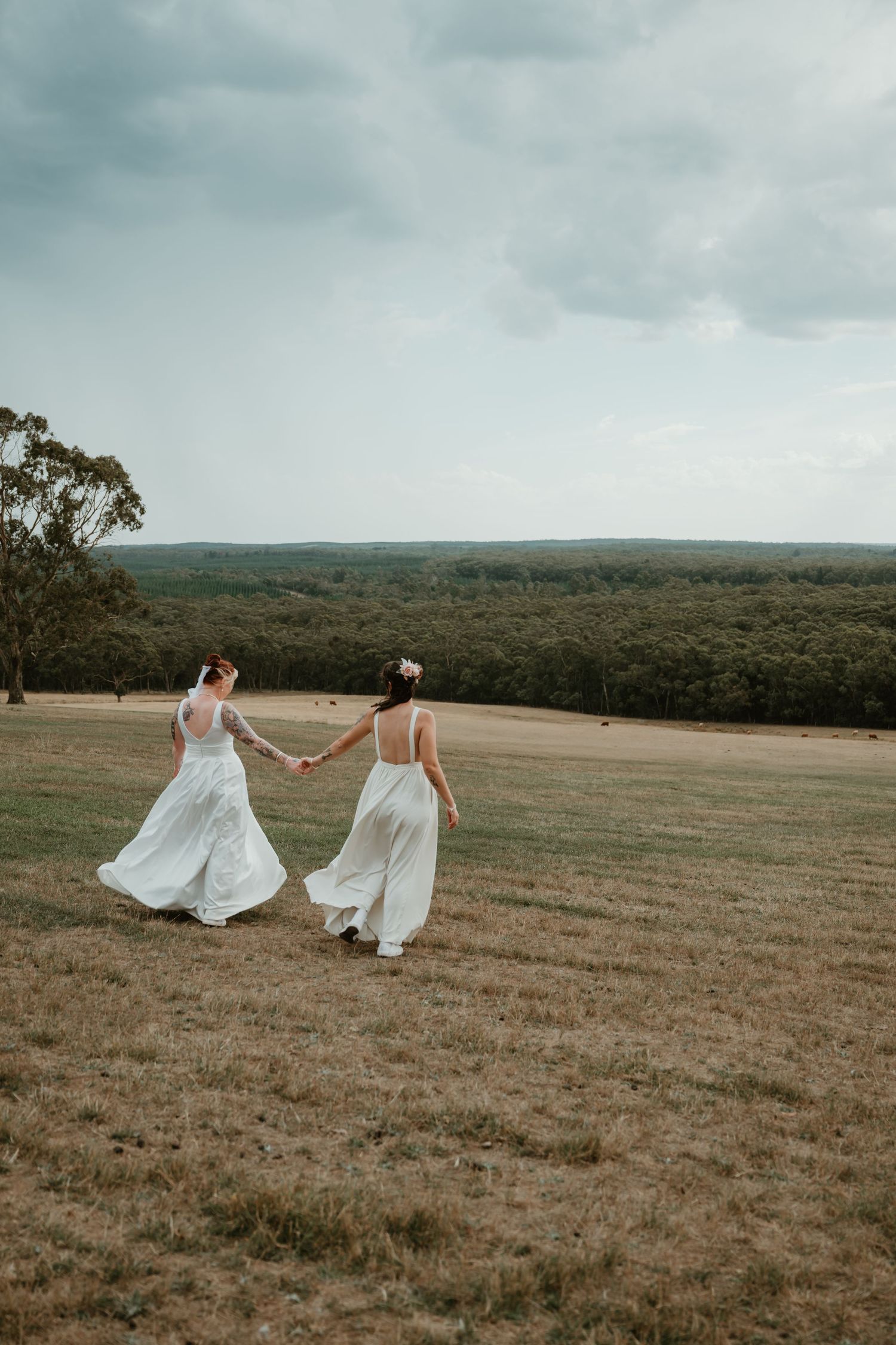 Dreamy wedding photo of couples in white dresses running through an open field.