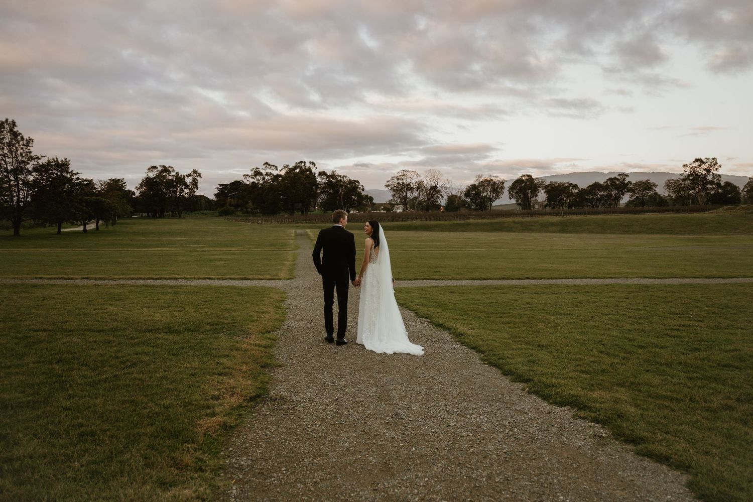 Panoramic landscape view of a romantic wedding ceremony setup in an open field at dusk.
