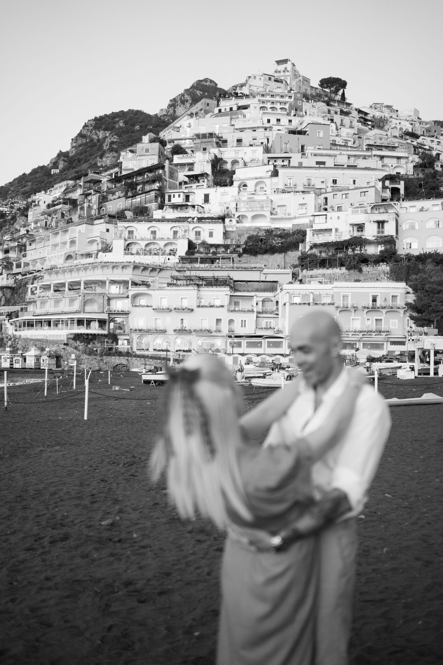 A black and white photo of dancing figures against Positano's hillside architecture.