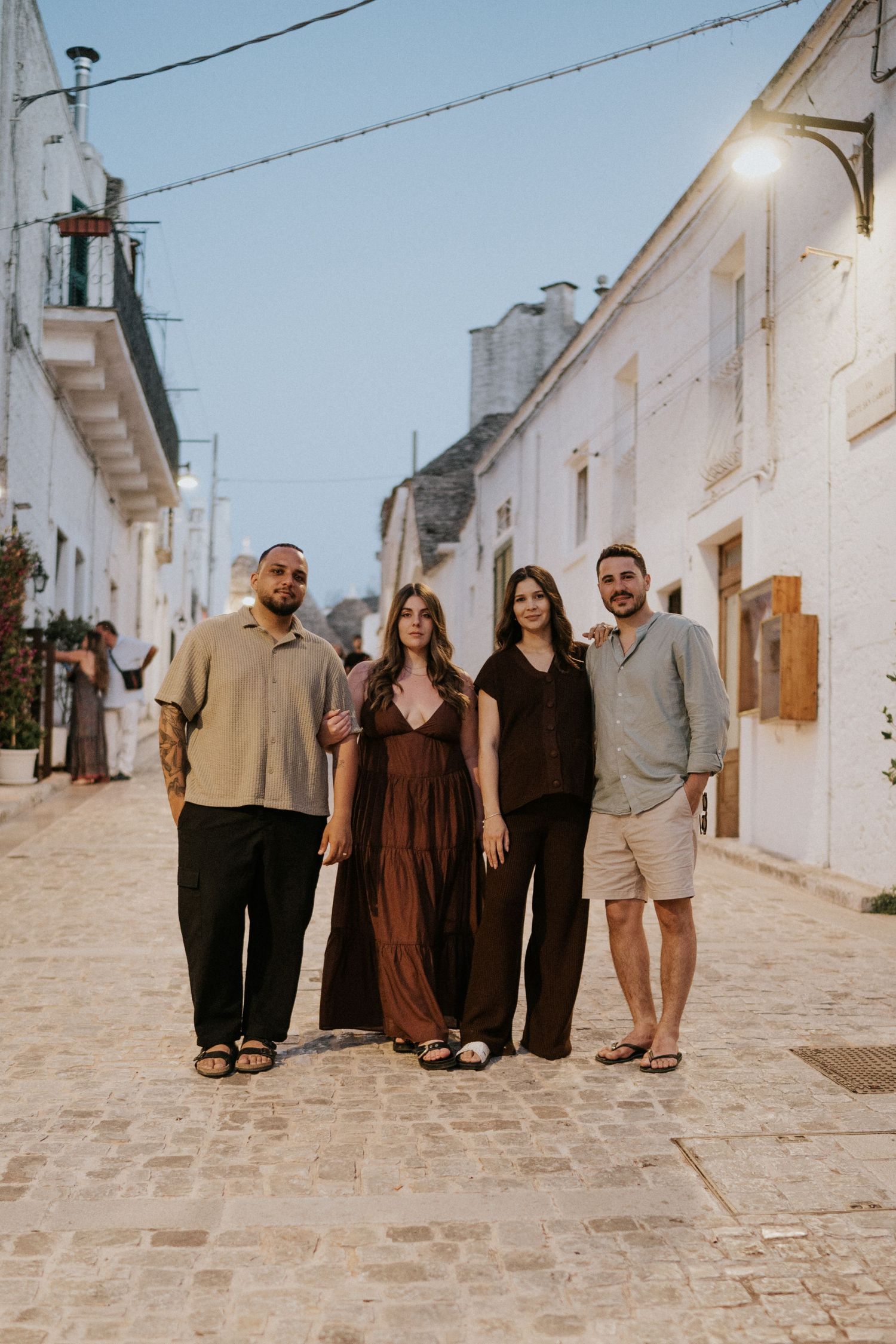 A group poses together on a charming white cobblestone street in a Mediterranean village.