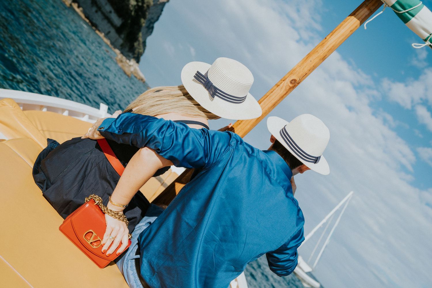 Tourists in blue clothing and sun hats enjoying a scenic boat ride along the coast.