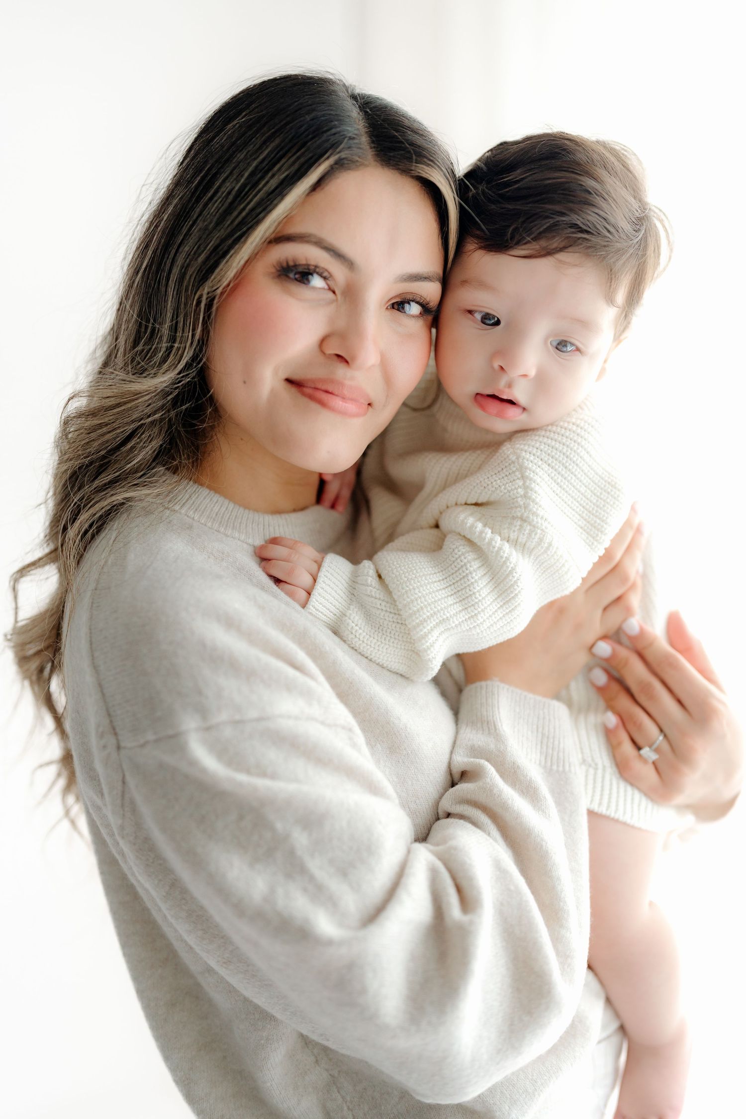 A series of tender embraces between two people in white sweaters against a light background.