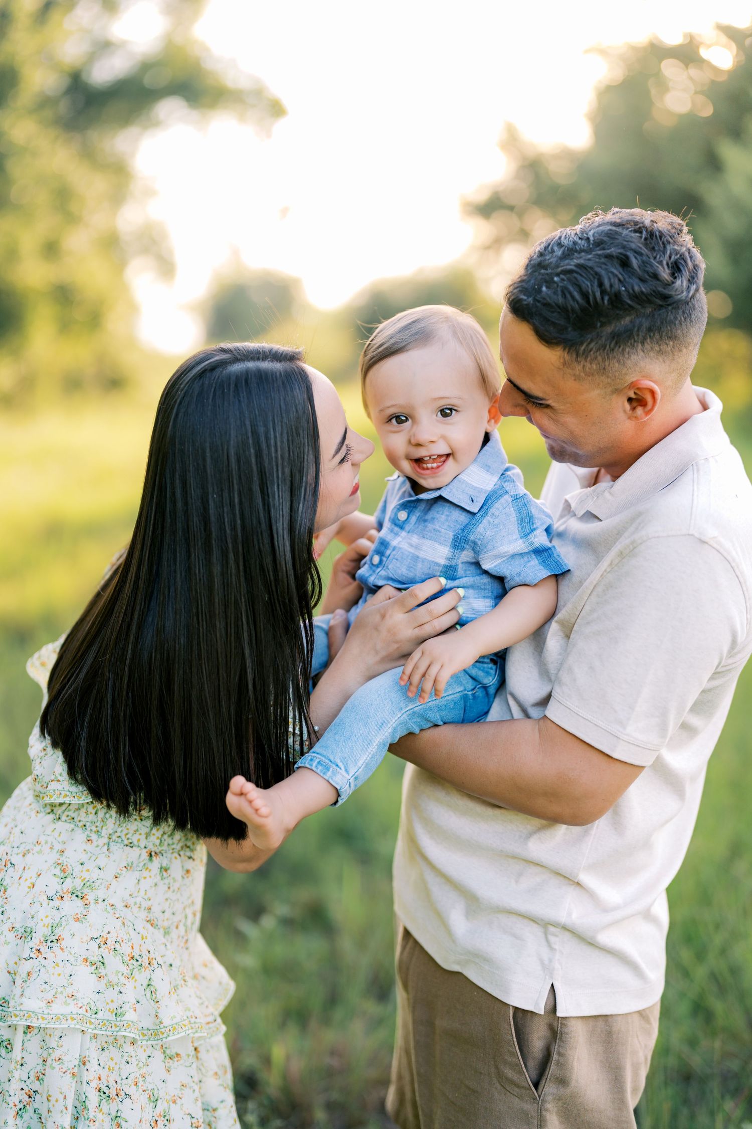 A family shares a tender moment together outdoors during a sunny portrait session in nature.